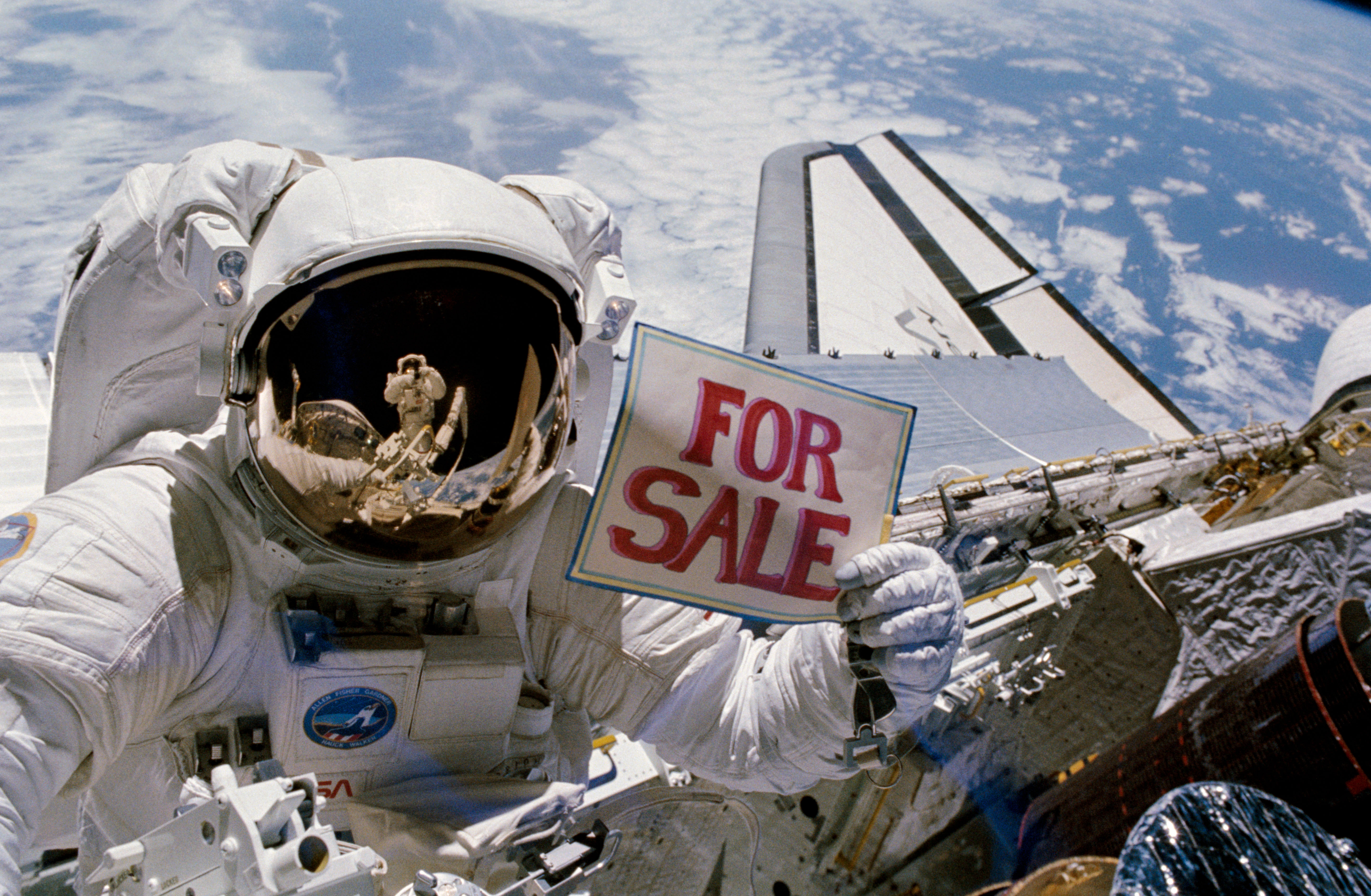 Astronaut Dale Gardner holds up for sale sign after EVA