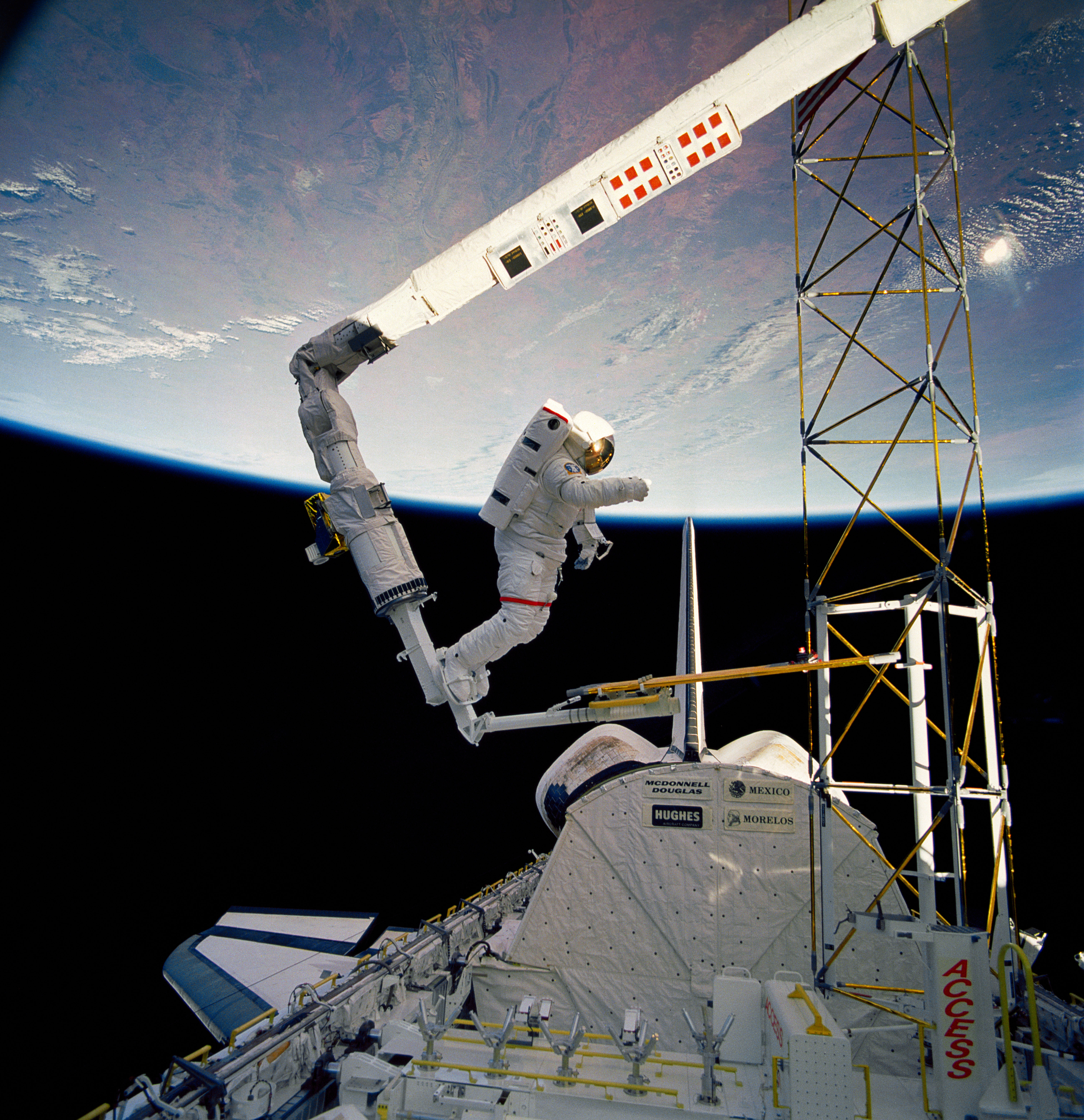 Astronaut Jerry Ross on RMS holds on to ACCESS device