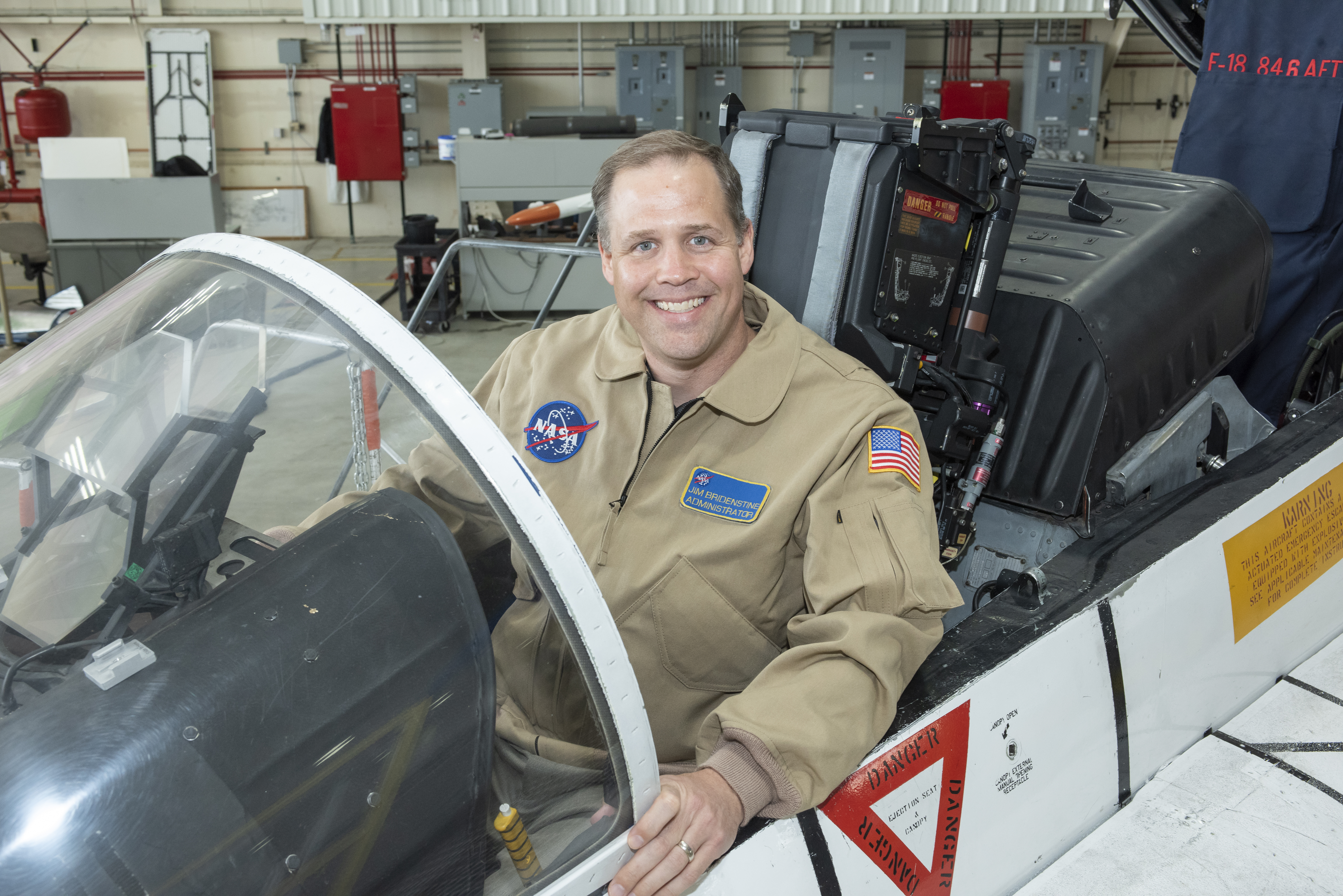 NASA Administrator Bridenstine sits in F-18 jet cockpit in NASA Armstrong Flight Research Center hangar in California where he did a Facebook Live event.