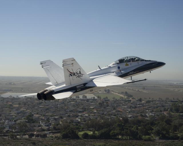 A NASA F/A‑18 aircraft flies in clear skies above Huntington Beach, California.