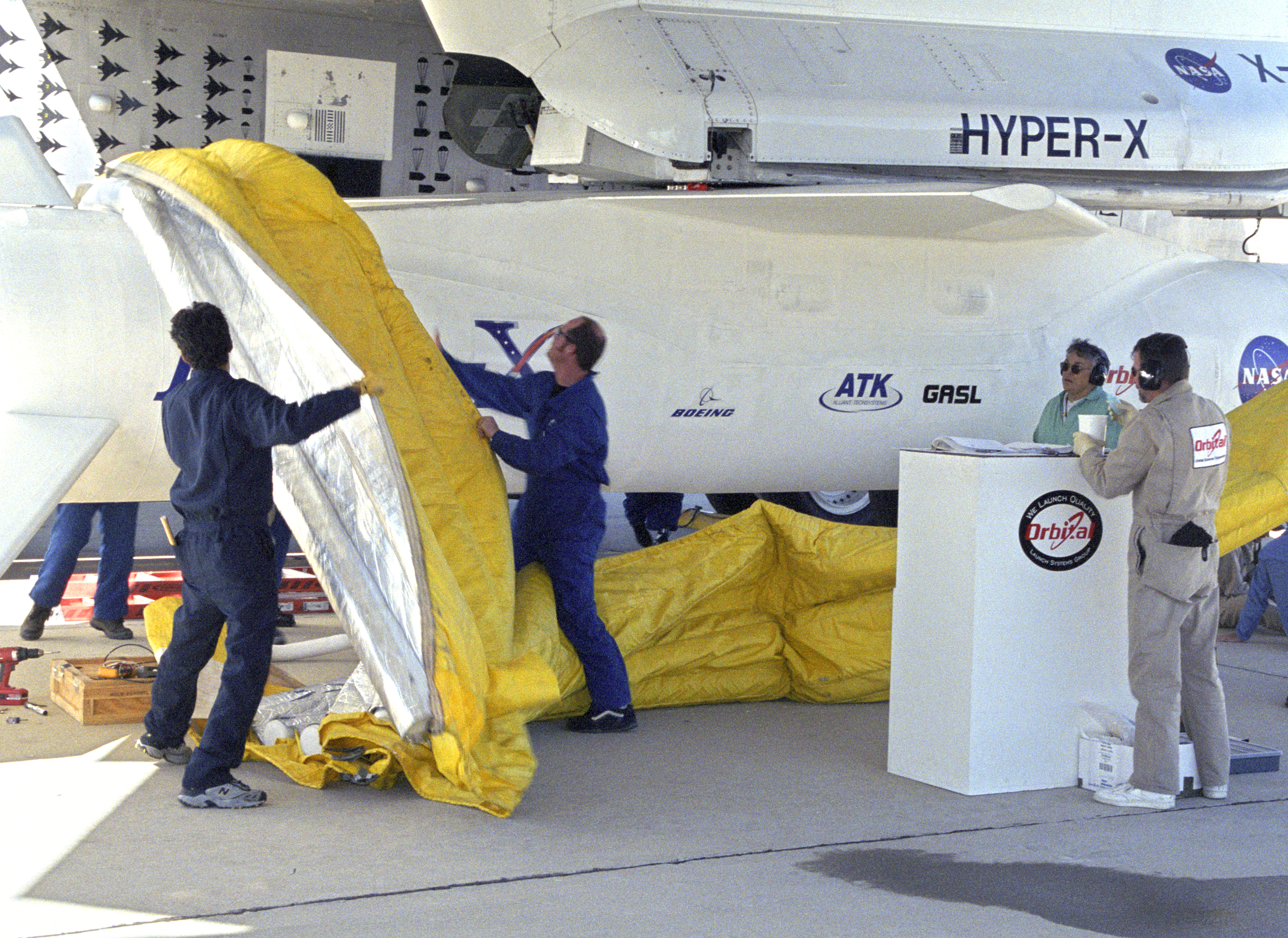 Orbital Sciences Corp. technicians remove protective shrouds from the modified Pegasus booster before takeoff on the X-43A's Mach 9.6 record scramjet flight