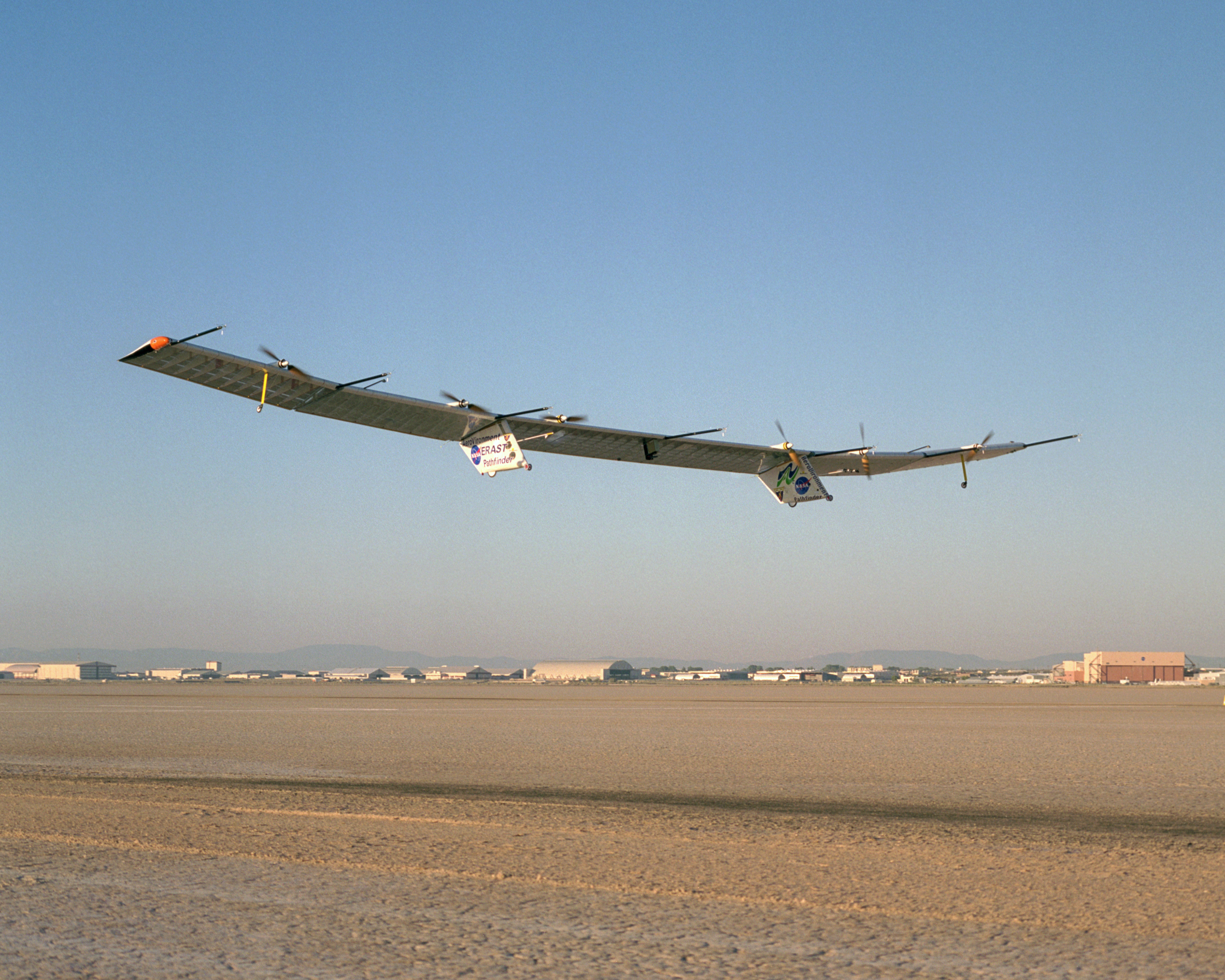With turbulence-measurement booms projecting ahead of the wing, Pathfinder-Plus soars aloft over Rogers Dry Lake on its final research flight from NASA Dryden.