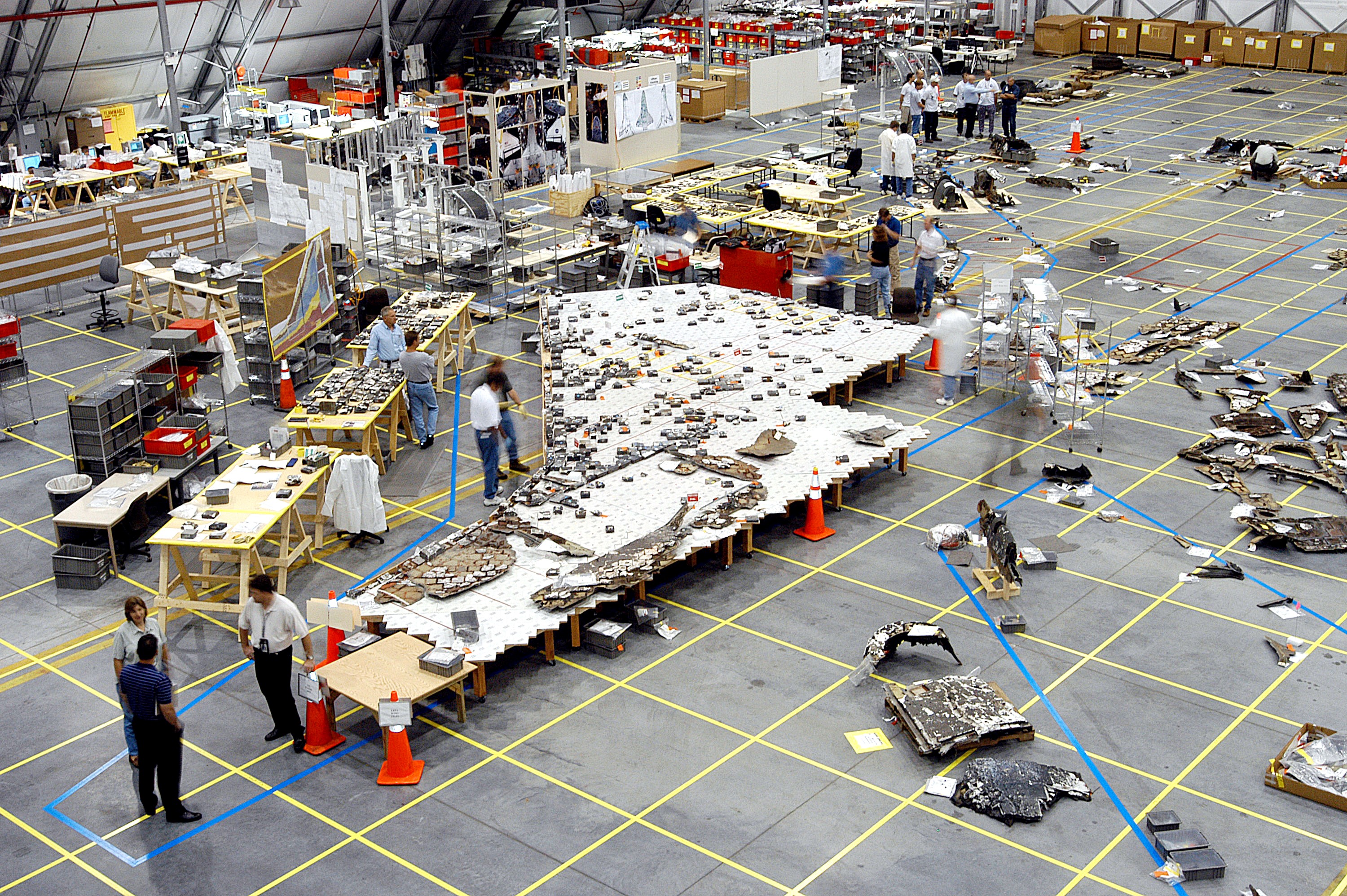 KENNEDY SPACE CENTER, FLA. - In the RLV hangar, members of the Columbia Reconstruction Team work to identify pieces of Thermal Protection System tile from the left wing of Columbia recovered during the search and recovery efforts in East Texas. The items shipped to KSC number more than 82,000 and weigh 84,800 pounds or 38 percent of the total dry weight of Columbia. Of those items, 78,760 have been identified, with 753 placed on the left wing grid in the Hangar.