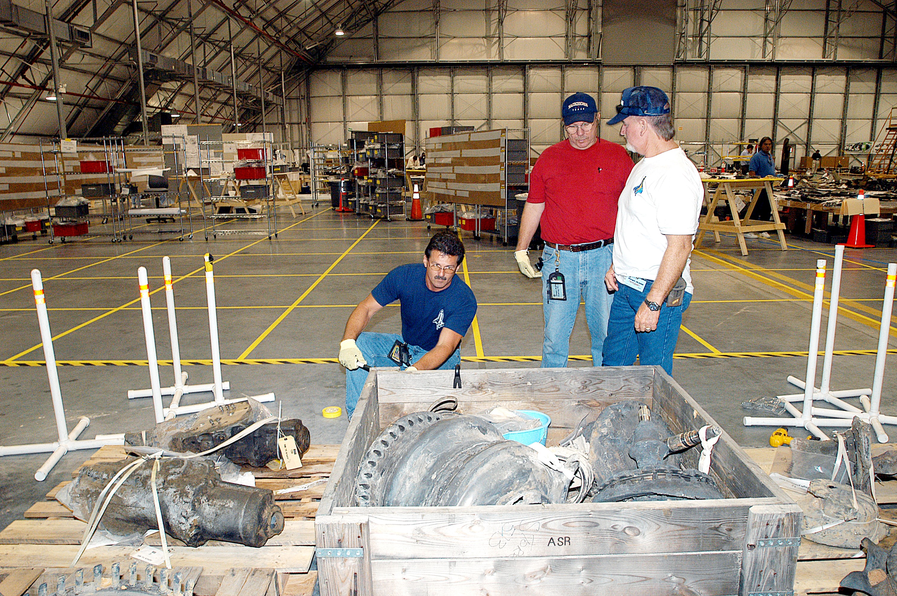 KENNEDY SPACE CENTER, FLA. - Members of the Columbia Reconstruction Project Team work with pieces of debris in the RLV Hangar. The items shipped to KSC number more than 82,000 and weigh 84,800 pounds or 38 percent of the total dry weight of Columbia. Of those items, 78,760 have been identified, with 753 placed on the left wing grid in the Hangar.
