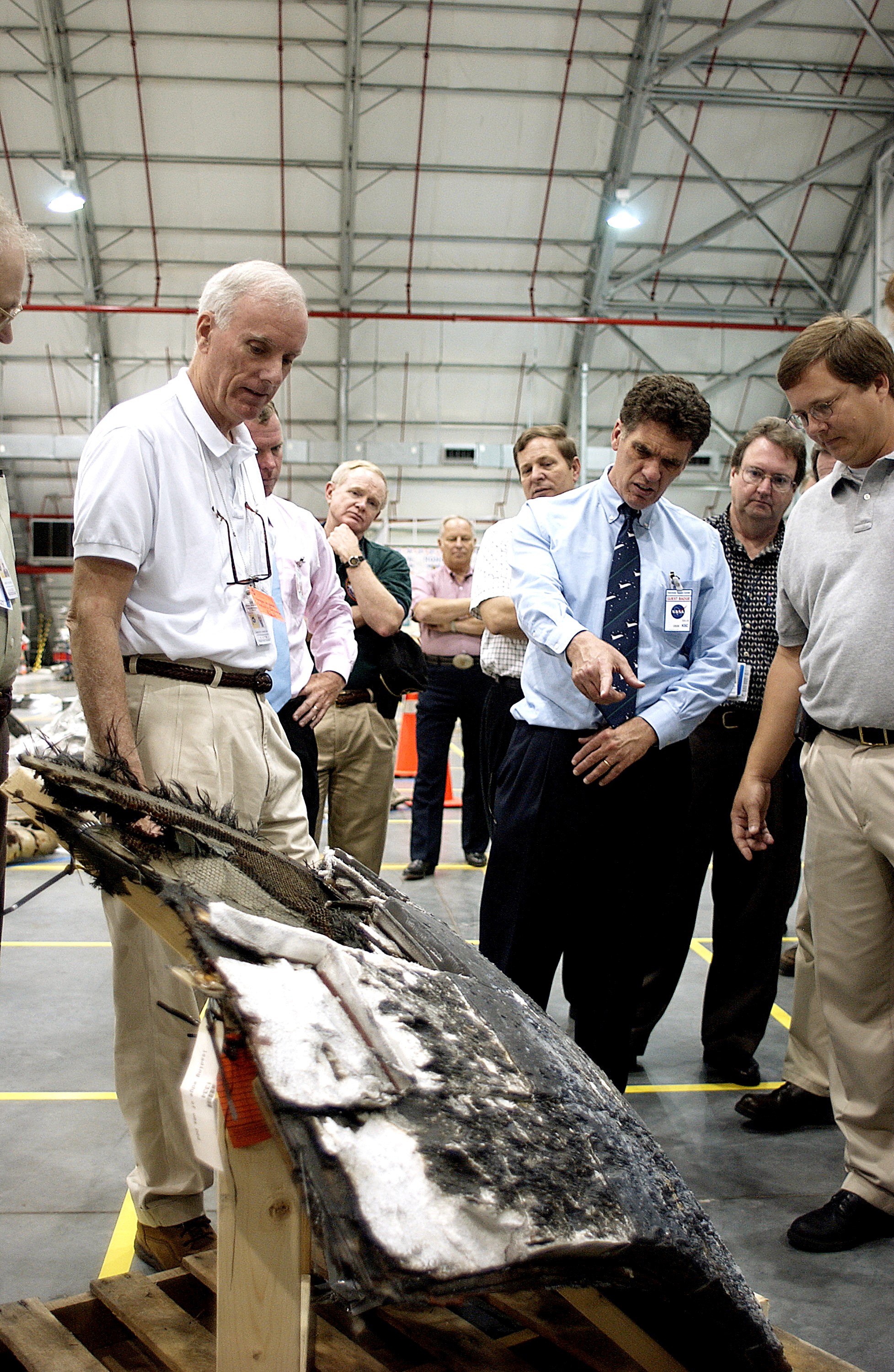 KENNEDY SPACE CENTER, FLA. - In the RLV Hangar, Adm. Harold Gehman, center, chairman of the Columbia Investigation Accident Board, looks on while U.S. Representative Dave Weldon (second from right) points at a piece of Columbia debris. Behind Gehman is U.S. Representative Tom Feeney. Gehman and other board members are visiting KSC as part of the ongoing investigation. Recovery efforts as of May 5 included 82,500 pieces of debris weighing 84,800 pounds, almost 40 percent of the total dry weight of the shuttle. About 25,000 personnel took part, utilizing almost 1.5 million total man-hours in the recovery effort and involving more than 130 federal, state and local agencies. The operation was also supported by more than 270 organizations that included businesses and volunteer groups.