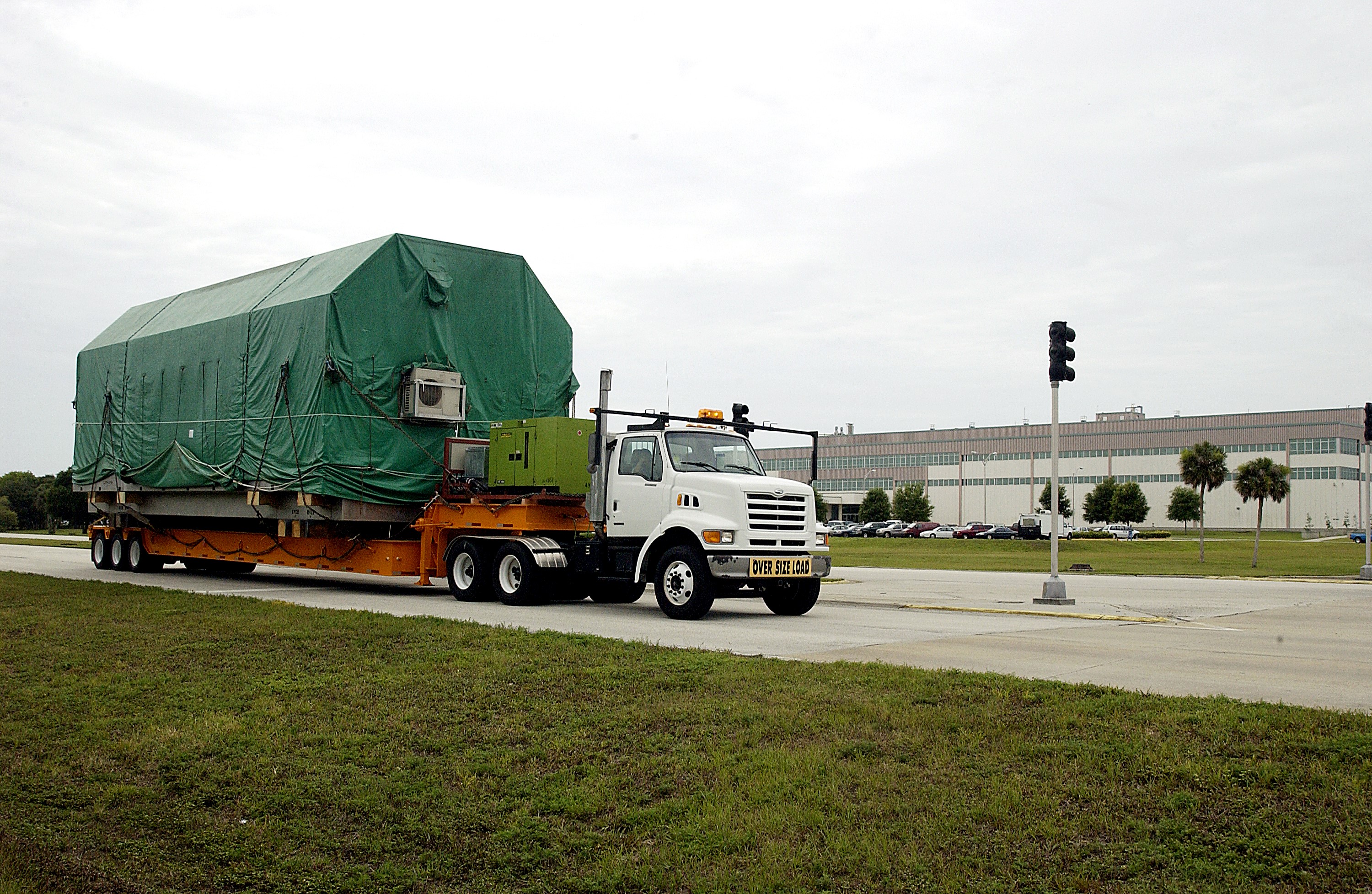 KENNEDY SPACE CENTER, FLA. - The truck transporting the Pressurized Module of the Japanese Experiment Module (JEM) to KSC’s Space Station Processing Facility arrives on Center. The National Space Development Agency of Japan (NASDA) developed the laboratory at the Tsukuba Space Center near Tokyo. The Pressurized Module is the first element of the JEM, named "Kibo" (Hope), to be delivered to KSC. The JEM is Japan's primary contribution to the Station. It will enhance the unique research capabilities of the orbiting complex by providing an additional environment for astronauts to conduct science experiments. The JEM also includes an exposed facility (platform) for space environment experiments, a robotic manipulator system, and two logistics modules. The various JEM components will be assembled in space over the course of three Shuttle missions.