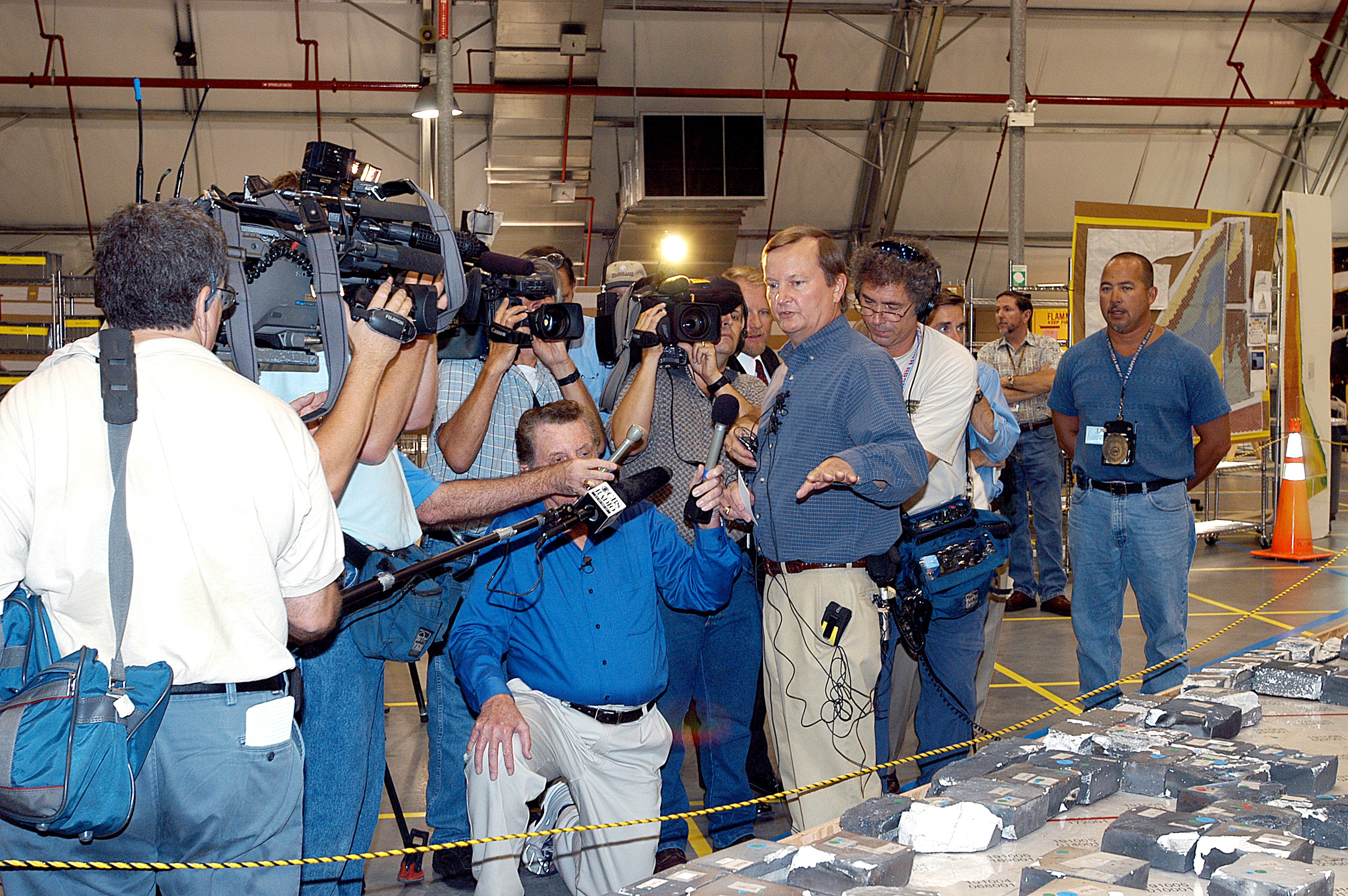 KENNEDY SPACE CENTER, FLA. - In the Columbia Debris Hangar, Shuttle Launch Director Mike Leinbach points to some of the tiles recovered from the orbiter as he explains to the media about activities that have taken place since the Columbia accident on Feb. 1, 2003. STS-107 debris recovery and reconstruction operations are winding down. To date, nearly 84,000 pieces of debris have been recovered and sent to KSC. That represents about 38 percent of the dry weight of Columbia, equaling almost 85,000 pounds.