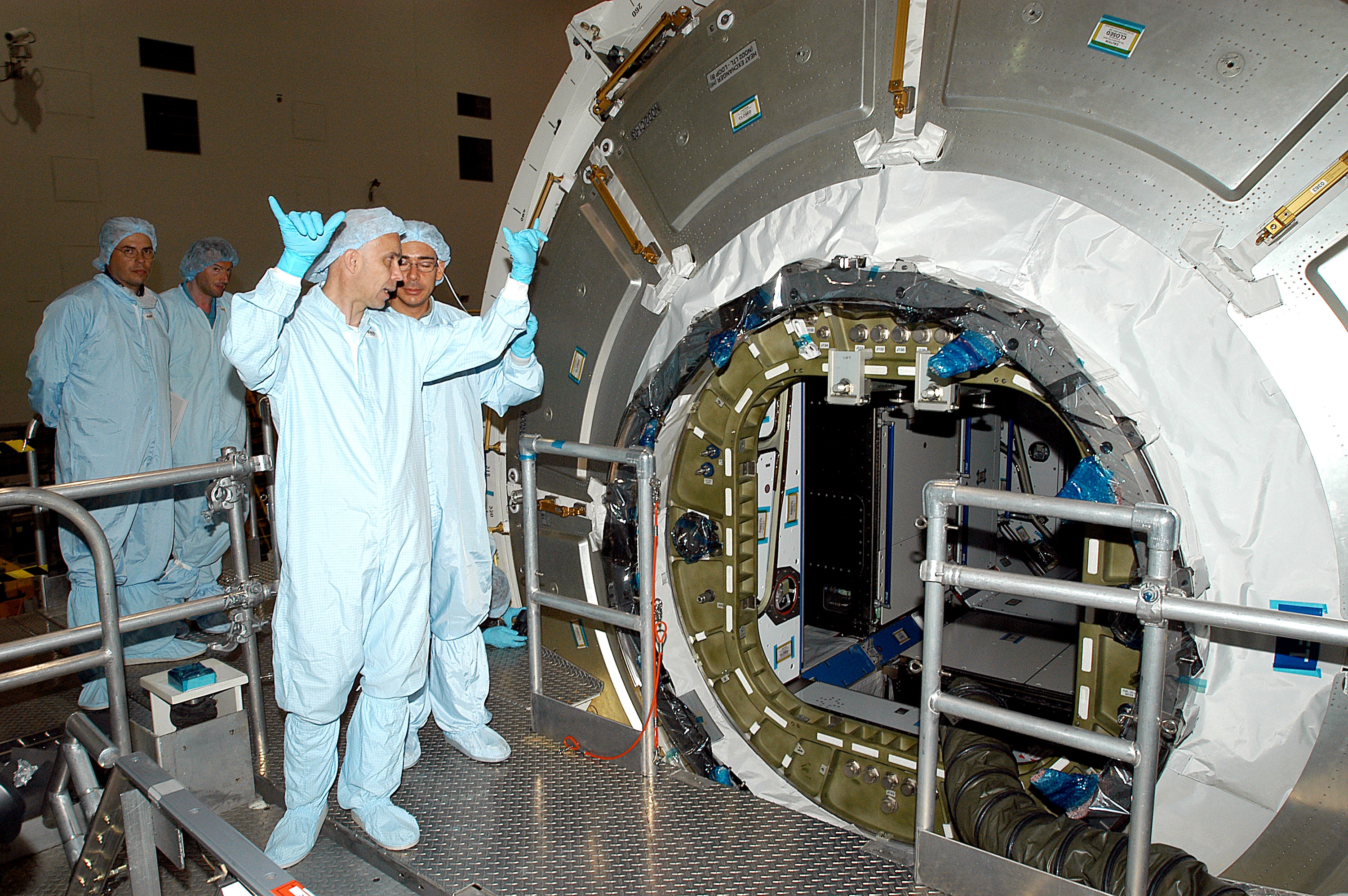 KENNEDY SPACE CENTER, FLA. - In the Space Station Processing Facility, workers talk near the opened hatch of the Italian-built Node 2. A future element of the International Space Station, Node 2 arrived at KSC June 1. The second of three Station connecting modules, Node 2 attaches to the end of the U.S. Lab and provides attach locations for the Japanese laboratory, European laboratory, the Centrifuge Accommodation Module and, later, Multipurpose Logistics Modules. It will provide the primary docking location for the Shuttle when a pressurized mating adapter is attached to Node 2. Installation of the module will complete the U.S. Core of the ISS. Node 2 is the designated payload for mission STS-120. No orbiter or launch date has been determined yet.
