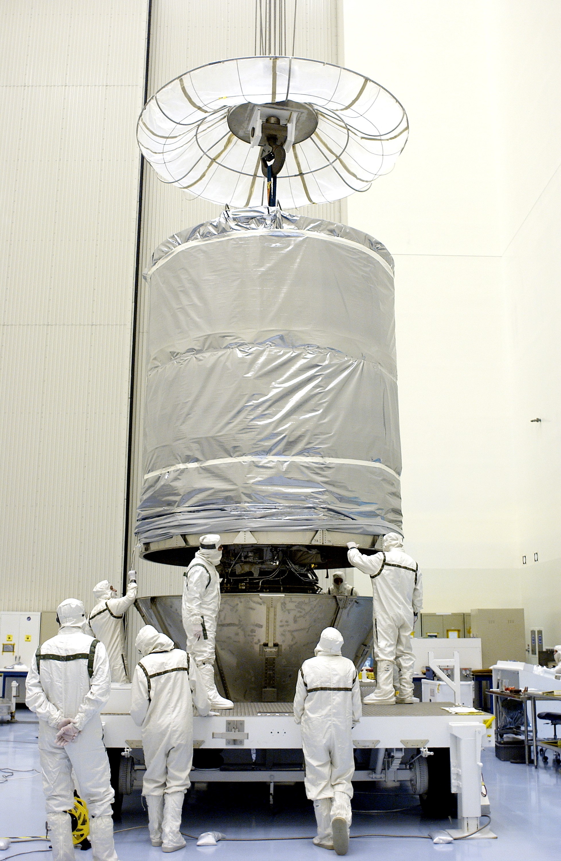 KENNEDY SPACE CENTER, FLA. - In the Payload Hazardous Servicing Facility, workers maneuver the cylindrical payload canister into place around Mars Exploration Rover 1 (MER-B). Once secure inside the canister, the rover will be transported to Launch Complex 17-B, Cape Canaveral Air Force Station, for mating with the Delta rocket. The second of twin rovers being sent to Mars, it is equipped with a robotic arm, a drilling tool, three spectrometers, and four pairs of cameras that allow it to have a human-like, 3D view of the terrain. Each rover could travel as far as 100 meters in one day to act as Mars scientists' eyes and hands, exploring an environment where humans can't yet go. MER-B is scheduled to launch from Pad 17-B June 26 at one of two available times, 12:27:31 a.m. EDT or 1:08:45 a.m. EDT.