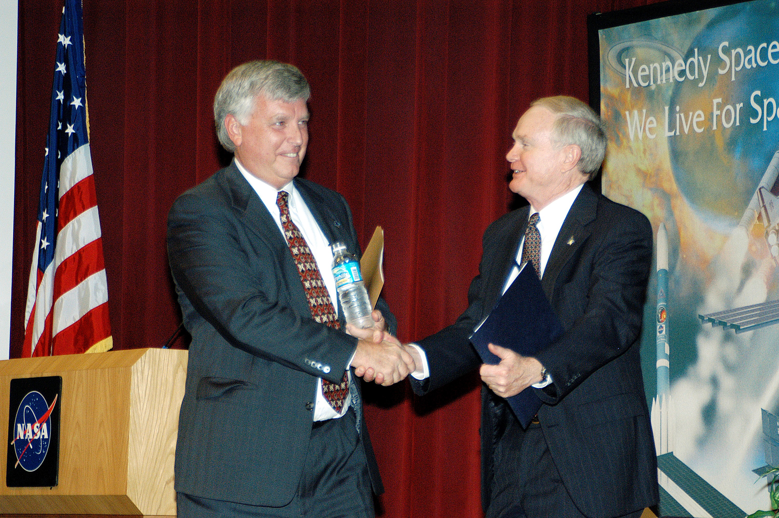 KENNEDY SPACE CENTER, FLA. - KSC Deputy Director James W. Kennedy (left) and KSC Director Roy D. Bridges shake hands before a group of KSC employees assembled in the KSC Training Auditorium. The occasion is the announcement of Kennedy as the next director of the NASA Kennedy Space Center (KSC) in Florida. Kennedy has served as KSC's deputy director since November 2002. He will succeed Bridges, who was appointed on June 13 to lead NASA's Langley Research Center, Hampton, Va.