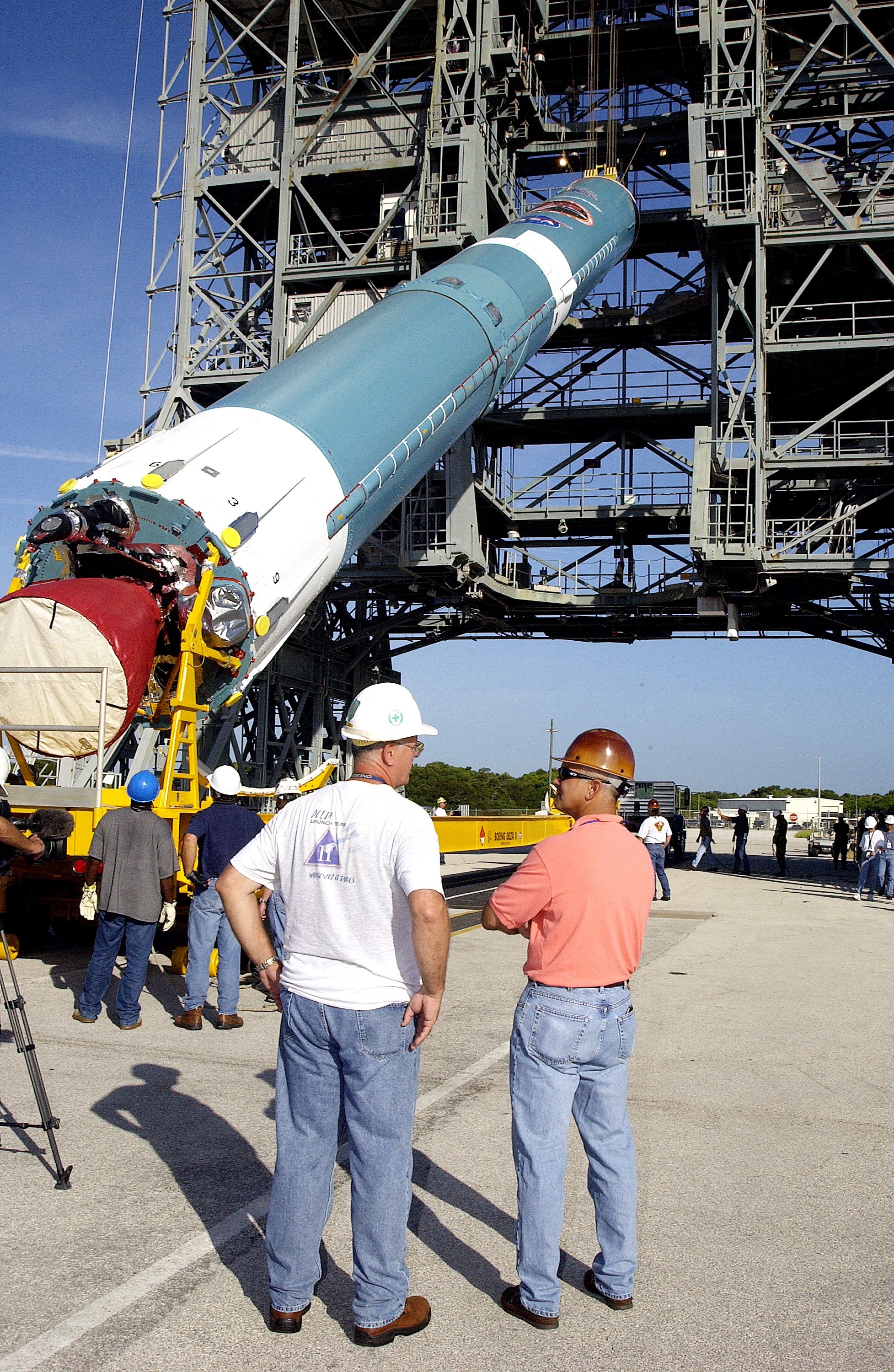KENNEDY SPACE CENTER, FLA. - On Launch Complex 17-B, Cape Canaveral Air Force Station, the first stage of a Delta II rocket is raised off the transporter before lifting it up and moved into the mobile service tower. The rocket is being erected to launch the Space InfraRed Telescope Facility (SIRTF). Consisting of an 0.85-meter telescope and three cryogenically cooled science instruments, SIRTF is one of NASA's largest infrared telescopes to be launched. SIRTF will obtain images and spectra by detecting the infrared energy, or heat, radiated by objects in space. Most of this infrared radiation is blocked by the Earth's atmosphere and cannot be observed from the ground.