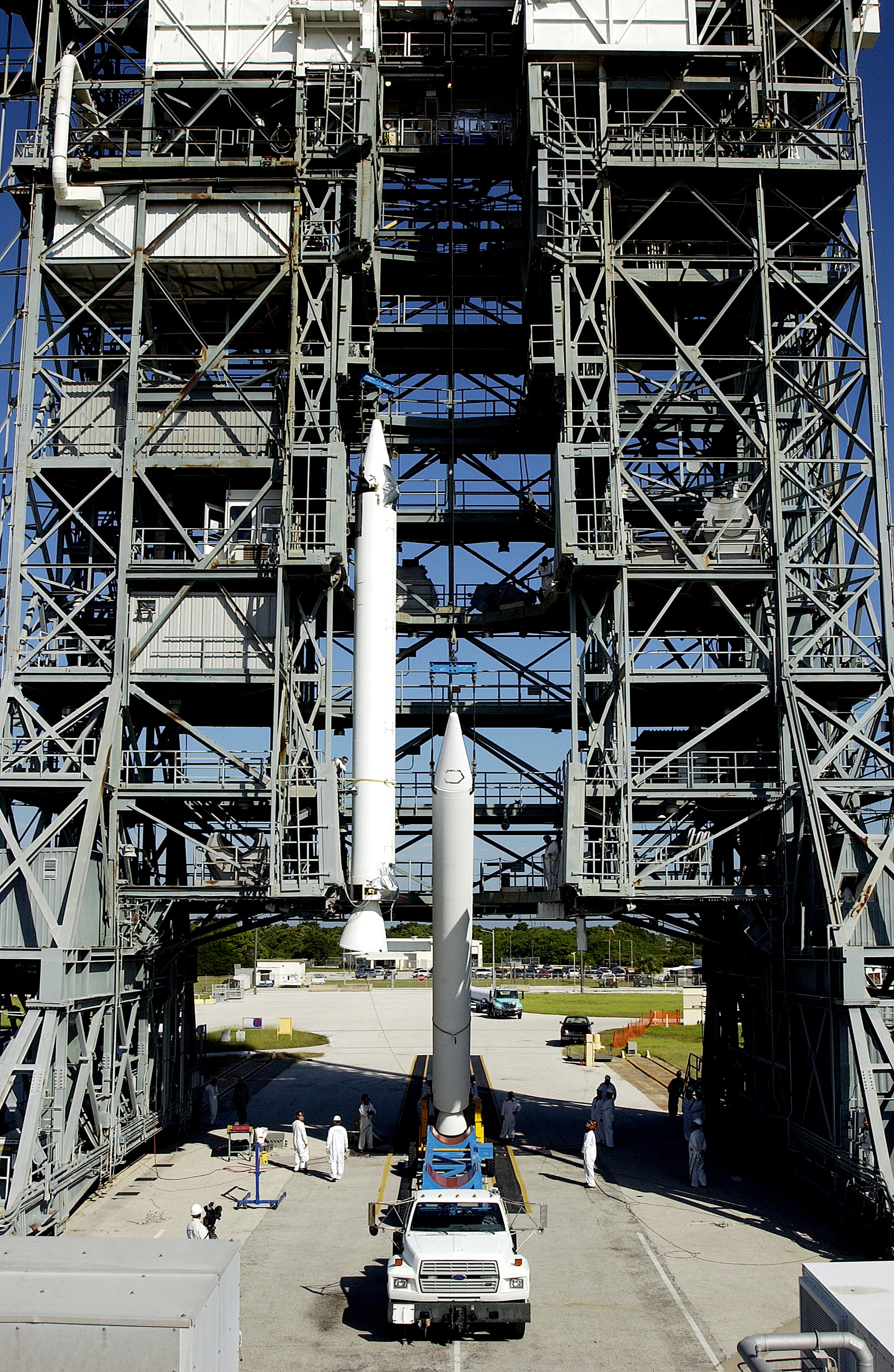 KENNEDY SPACE CENTER, FLA. - Another solid rocket booster (SRB) is lifted to vertical on Launch Complex 17-B, Cape Canaveral Air Force Station, to join the one already in place in the mobile service tower. The SRBs will be attached to the Delta II Heavy rocket that will launch the Space Infrared Telescope Facility (SIRTF). The Delta II Heavy features nine 46-inch-diameter, stretched SRBs. SIRTF, consisting of three cryogenically cooled science instruments and an 0.85-meter telescope, is one of NASA's largest infrared telescopes to be launched. SIRTF will obtain images and spectra by detecting the infrared energy, or heat, radiated by objects in space. Most of this infrared radiation is blocked by the Earth's atmosphere and cannot be observed from the ground.