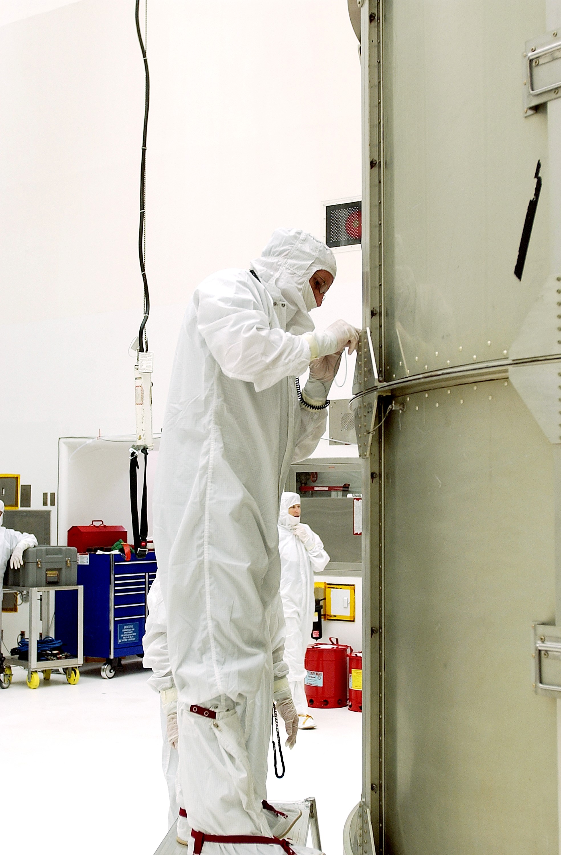 KENNEDY SPACE CENTER, FLA. - A worker at Hangar A&E, Cape Canaveral Air Force Station, tightens the canister around the Space Infrared Telescope Facility (SIRTF). The spacecraft will be transported to Launch Complex 17-B for mating with its launch vehicle, the Delta II rocket. SIRTF consists of three cryogenically cooled science instruments and an 0.85-meter telescope, and is one of NASA's largest infrared telescopes to be launched. SIRTF will obtain images and spectra by detecting the infrared energy, or heat, radiated by objects in space. Most of this infrared radiation is blocked by the Earth's atmosphere and cannot be observed from the ground.