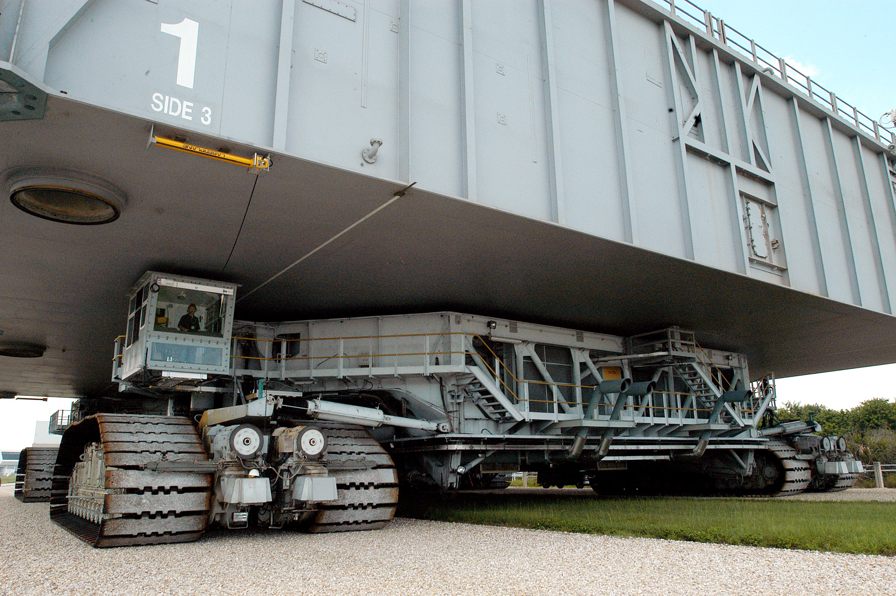 KENNEDY SPACE CENTER, FLA. - A closeup of crawler-transporter (CT) number 2 shows the cab (left, above the tracks) that recently underwent modifications. The CT is transporting a Mobile Launch Platform (MLP) on a test run to the pad. The CT moves Space Shuttle vehicles, situated on the MLP, between the VAB and launch pad. Moving on four double-tracked crawlers, the CT uses a laser guidance system and a leveling system for the journey that keeps the top of a Space Shuttle vertical within plus- or minus-10 minutes of arc. The system enables the CT-MLP-Shuttle to negotiate the ramp leading to the launch pads and keep the load level. Unloaded, the CT weighs 6 million pounds. Seen on top of the MLP are two tail service masts that support the fluid, gas and electrical requirements of the orbiter’s liquid oxygen and liquid hydrogen aft umbilicals.
