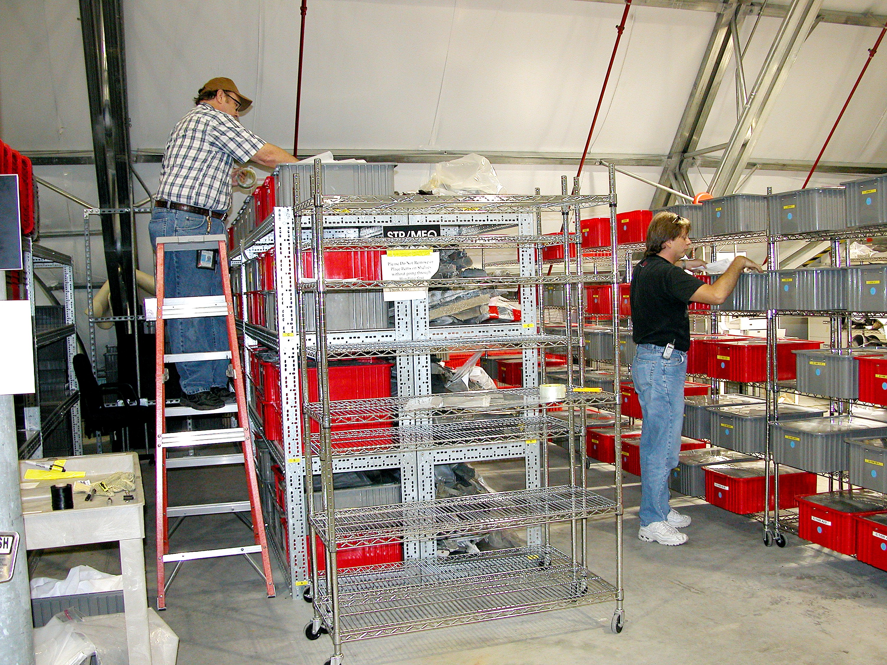 KENNEDY SPACE CENTER, FLA. - Workers in the Columbia Debris Hangar pull items from storage containers to transfer to storage in the Vehicle Assembly Building. About 83,000 pieces were shipped to KSC during search and recovery efforts in East Texas.