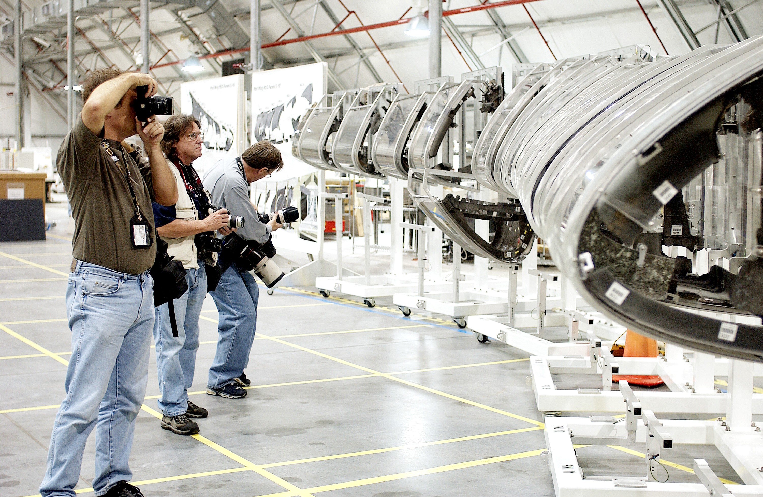 KENNEDY SPACE CENTER, FLA. - During a media tour of the Columbia Debris Hangar, photographers pause at the mockup of the leading edge of Columbia’s left wing. About 83,000 pieces of debris from Columbia were shipped to KSC from search and recovery efforts in East Texas. About 83,000 pieces of debris were shipped to KSC, which represents about 38 percent of the dry weight of Columbia, equaling almost 85,000 pounds. The debris is being packaged for storage in an area of the Vehicle Assembly Building.
