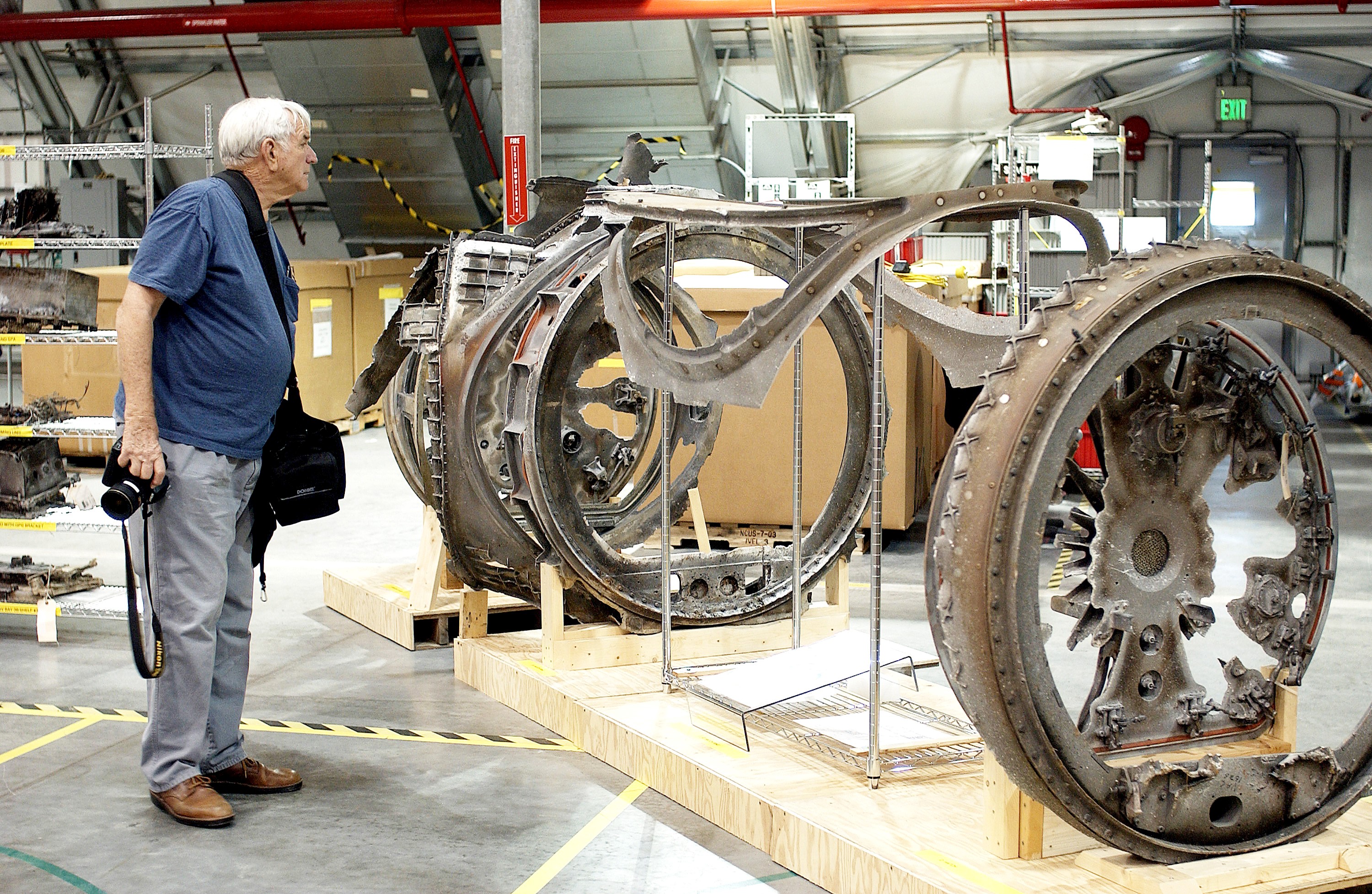 KENNEDY SPACE CENTER, FLA. - During a media tour of the Columbia Debris Hangar, a photographer examines some of the debris collected from search and recovery efforts in East Texas. About 83,000 pieces of debris from Columbia were shipped to KSC, which represents about 38 percent of the dry weight of Columbia, equaling almost 85,000 pounds. The debris is being packaged for storage in an area of the Vehicle Assembly Building.