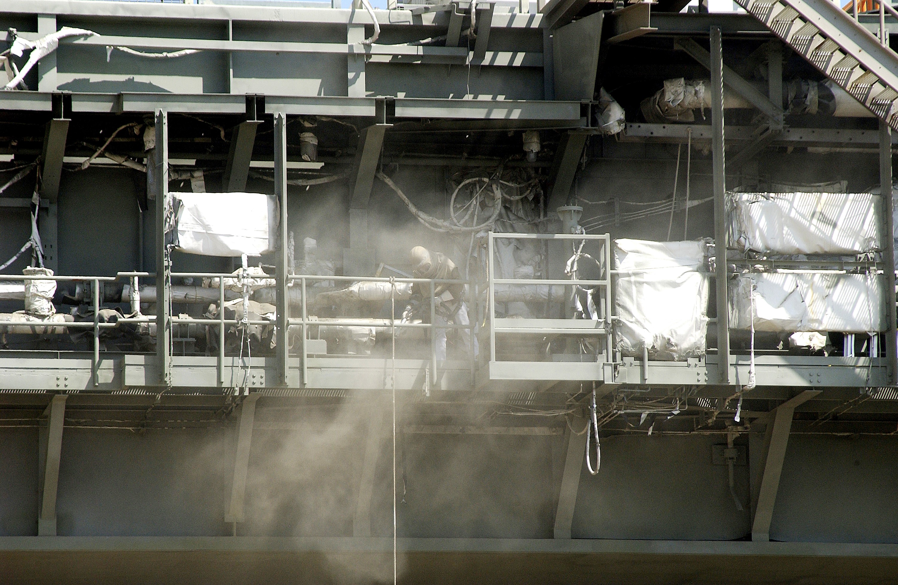KENNEDY SPACE CENTER, FLA. - Workers, covered in protective clothing and breathing apparatus, continue sandblasting on the Mobile Launcher Platform on Launch Pad 39A to remove corrosion before repainting. Routine maintenance includes sandblasting and repainting as preventive means to minimize corrosion.