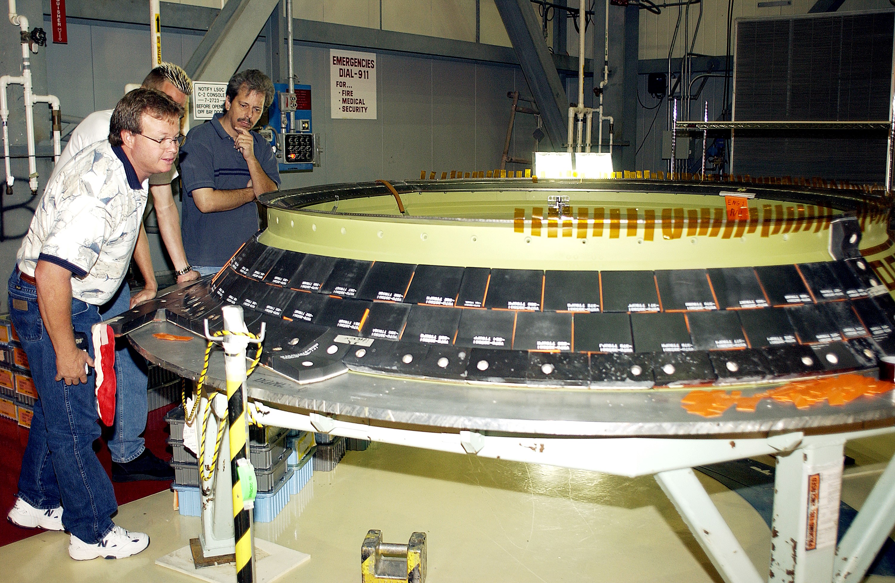 KENNEDY SPACE CENTER, FLA. - United Space Alliance employees (from left) Daryl Burke, Jay Beason and Tom Summers check new tiles installed on the heat shield of main engine 1 for the orbiter Discovery. A heat shield is a protective layer on a spacecraft designed to protect it from the high temperatures, usually those that result from aerobraking during reentry into the Earth’s atmosphere.