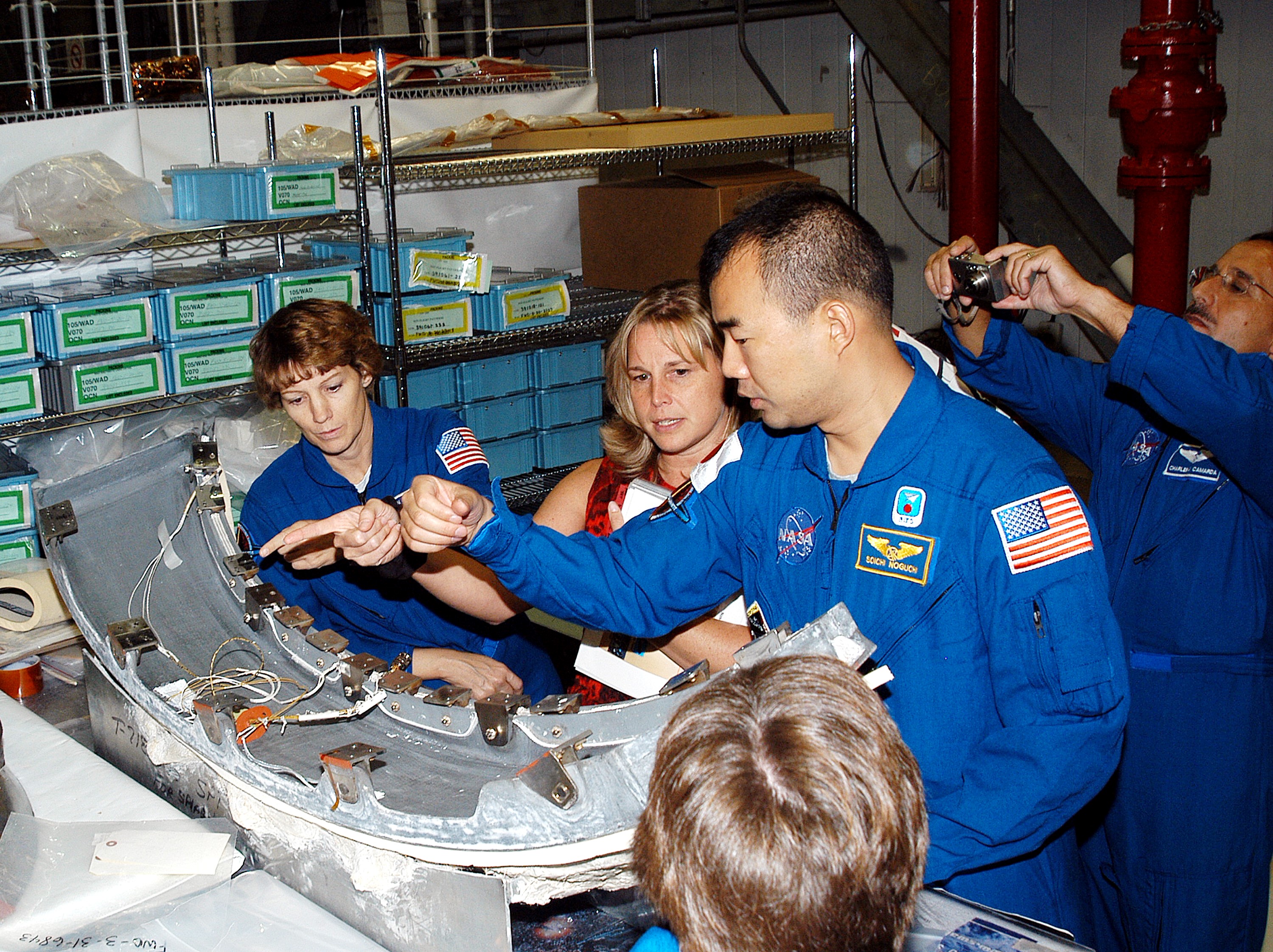 KENNEDY SPACE CENTER, FLA. - Members of the STS-114 crew look over flight equipment in the Orbiter Processing Facility. From left are Mission Commander Eileen Collins; Glenda Laws, EVA Task Leader, with United Space Alliance at Johnson Space Center; and Mission Specialists Soichi Noguchi and Charles Camarda. In the foreground is Mission Specialist Wendy Lawrence. Noguchi is with the Japan Aerospace Exploration Agency, JAXA. Not seen are Pilot James Kelly and Mission Specialists Andy Thomas and Stephen Robinson. The STS-114 crew is at KSC to take part in crew equipment and orbiter familiarization.