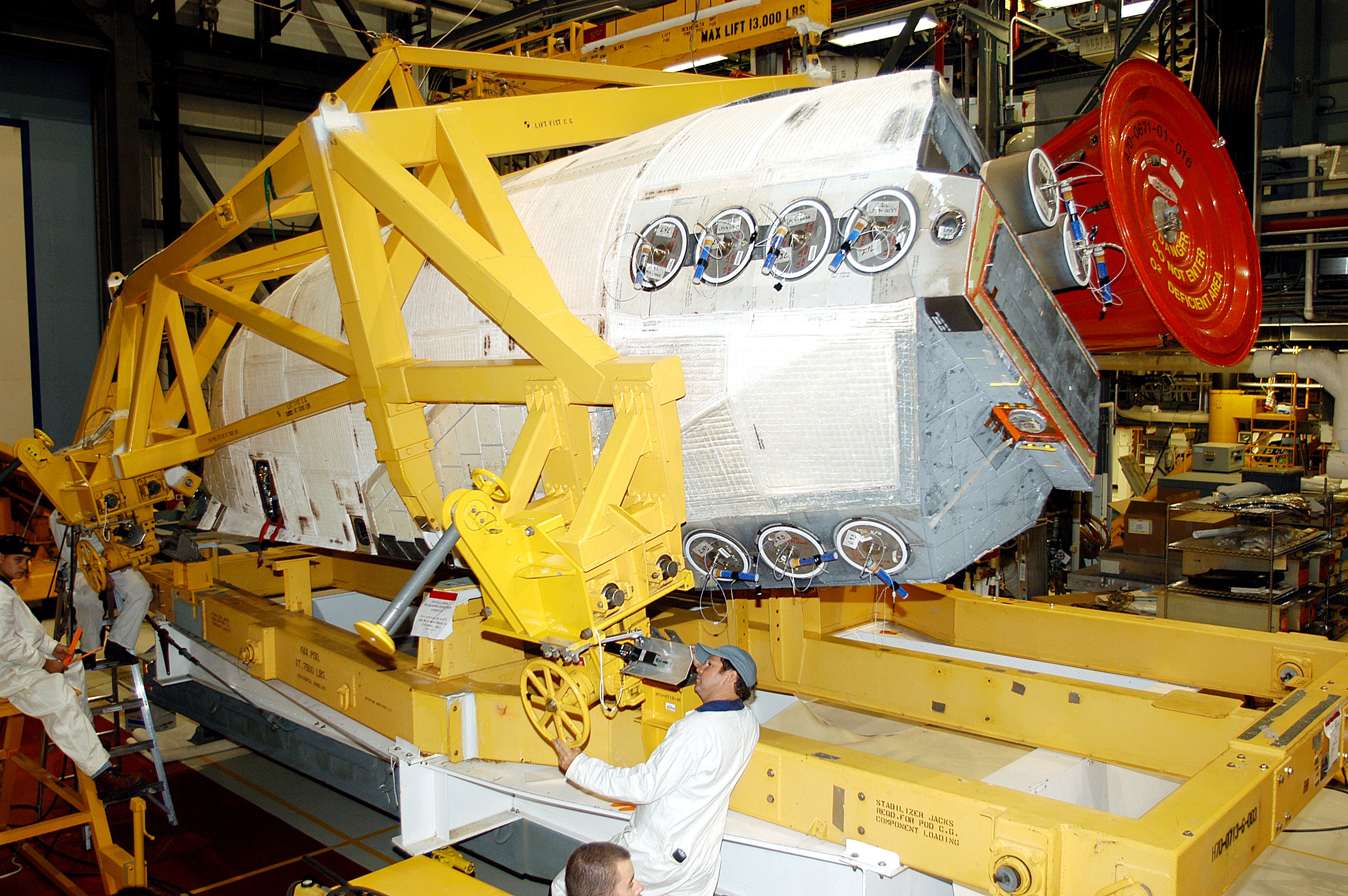 KENNEDY SPACE CENTER, FLA. - In the Orbiter Processing Facility, one of two orbital maneuvering system (OMS) pods is being moved for installation on Atlantis. The OMS pods are attached to the upper aft fuselage left and right sides. Fabricated primarily of graphite epoxy composite and aluminum, each pod is 21.8 feet long and 11.37 feet wide at its aft end and 8.41 feet wide at its forward end, with a surface area of approximately 435 square feet. Each pod houses the Reaction Control System propulsion components used for inflight maneuvering and is attached to the aft fuselage with 11 bolts.