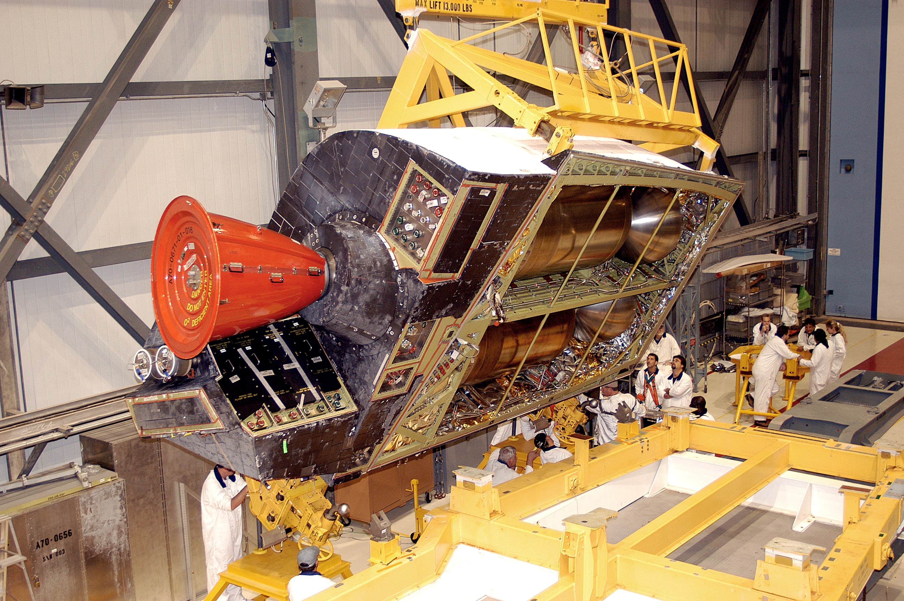 KENNEDY SPACE CENTER, FLA. - In the Orbiter Processing Facility, one of two orbital maneuvering system (OMS) pods is lifted off its stand to move it toward Atlantis for installation. The OMS pods are attached to the upper aft fuselage left and right sides. Fabricated primarily of graphite epoxy composite and aluminum, each pod is 21.8 feet long and 11.37 feet wide at its aft end and 8.41 feet wide at its forward end, with a surface area of approximately 435 square feet. Each pod houses the Reaction Control System propulsion components used for inflight maneuvering and is attached to the aft fuselage with 11 bolts.