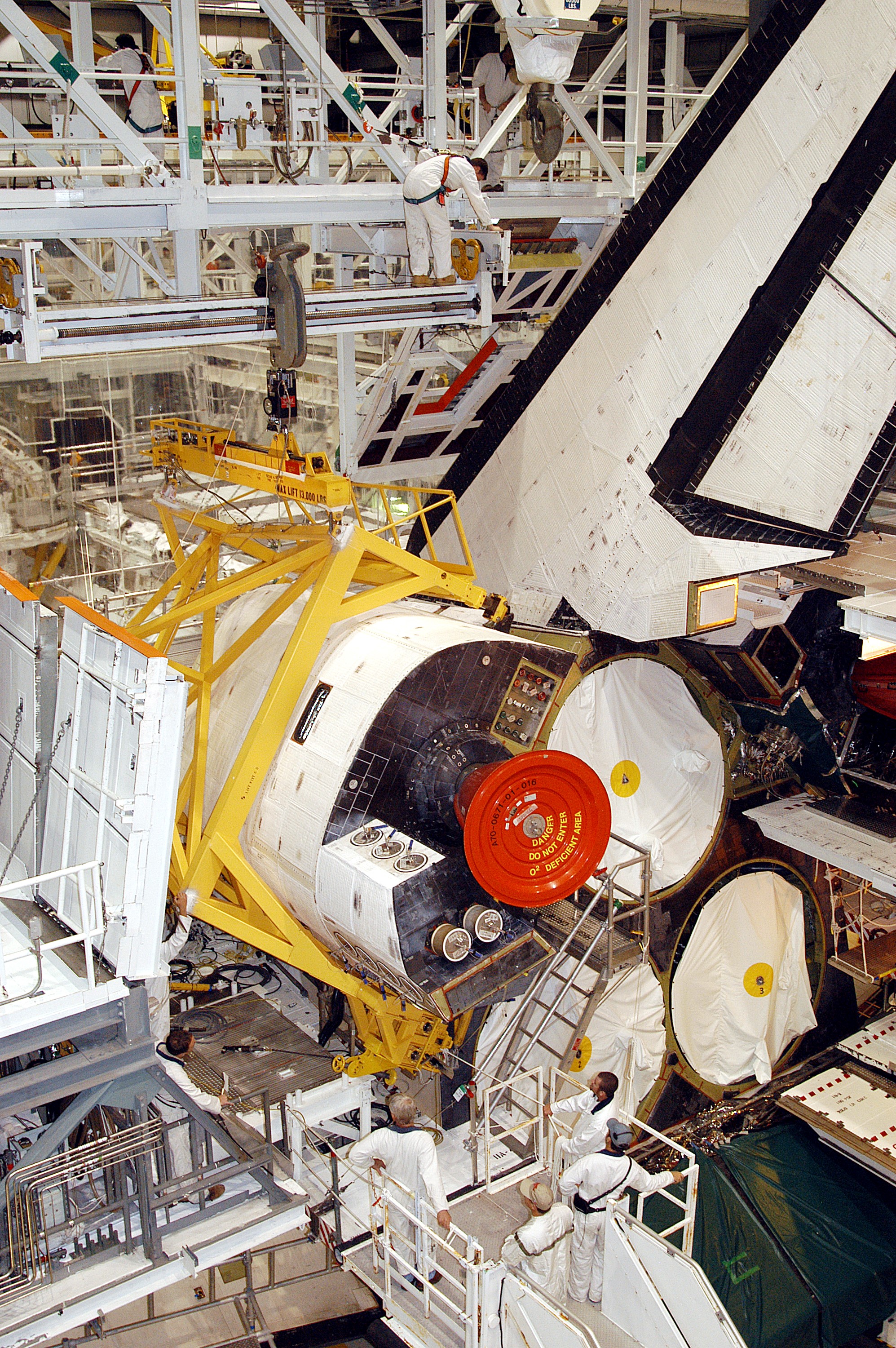 KENNEDY SPACE CENTER, FLA. - In the Orbiter Processing Facility, an orbital maneuvering system (OMS) pod is moved into place on Atlantis. It is one of two OMS pods attached to the upper aft fuselage left and right sides. Fabricated primarily of graphite epoxy composite and aluminum, each pod is 21.8 feet long and 11.37 feet wide at its aft end and 8.41 feet wide at its forward end, with a surface area of approximately 435 square feet. Each pod houses the Reaction Control System propulsion components used for inflight maneuvering and is attached to the aft fuselage with 11 bolts.