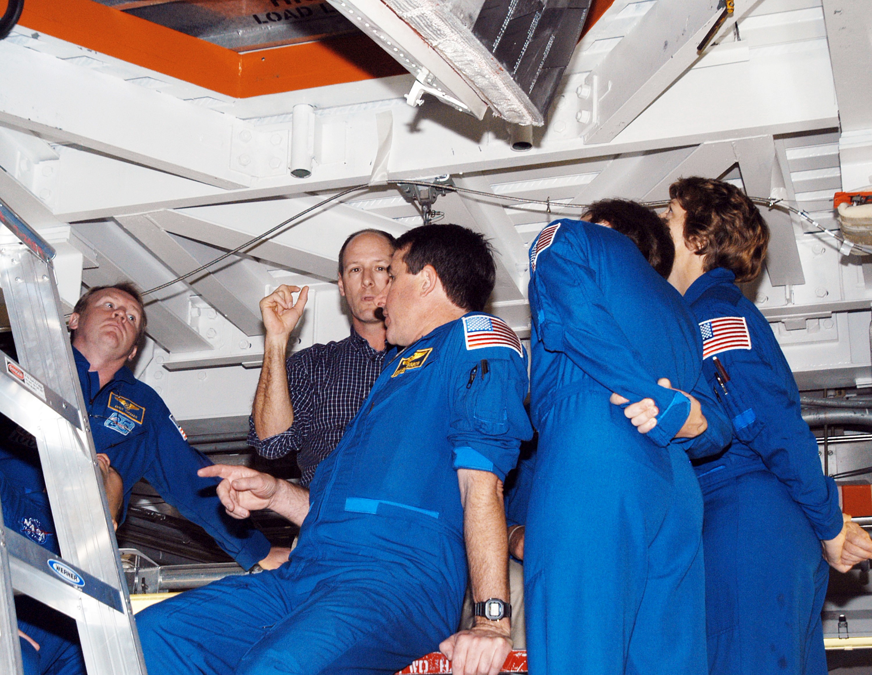 KENNEDY SPACE CENTER, FLA. - In the Orbiter Processing Facility, members of the STS-114 crew look up at the payload bay of orbiter Atlantis. From left (in flight suits) are Mission Specialists Andrew Thomas, Stephen Robinson and Charles Camarda, and Mission Commander Eileen Collins. The STS-114 crew is at KSC to take part in crew equipment and orbiter familiarization.
