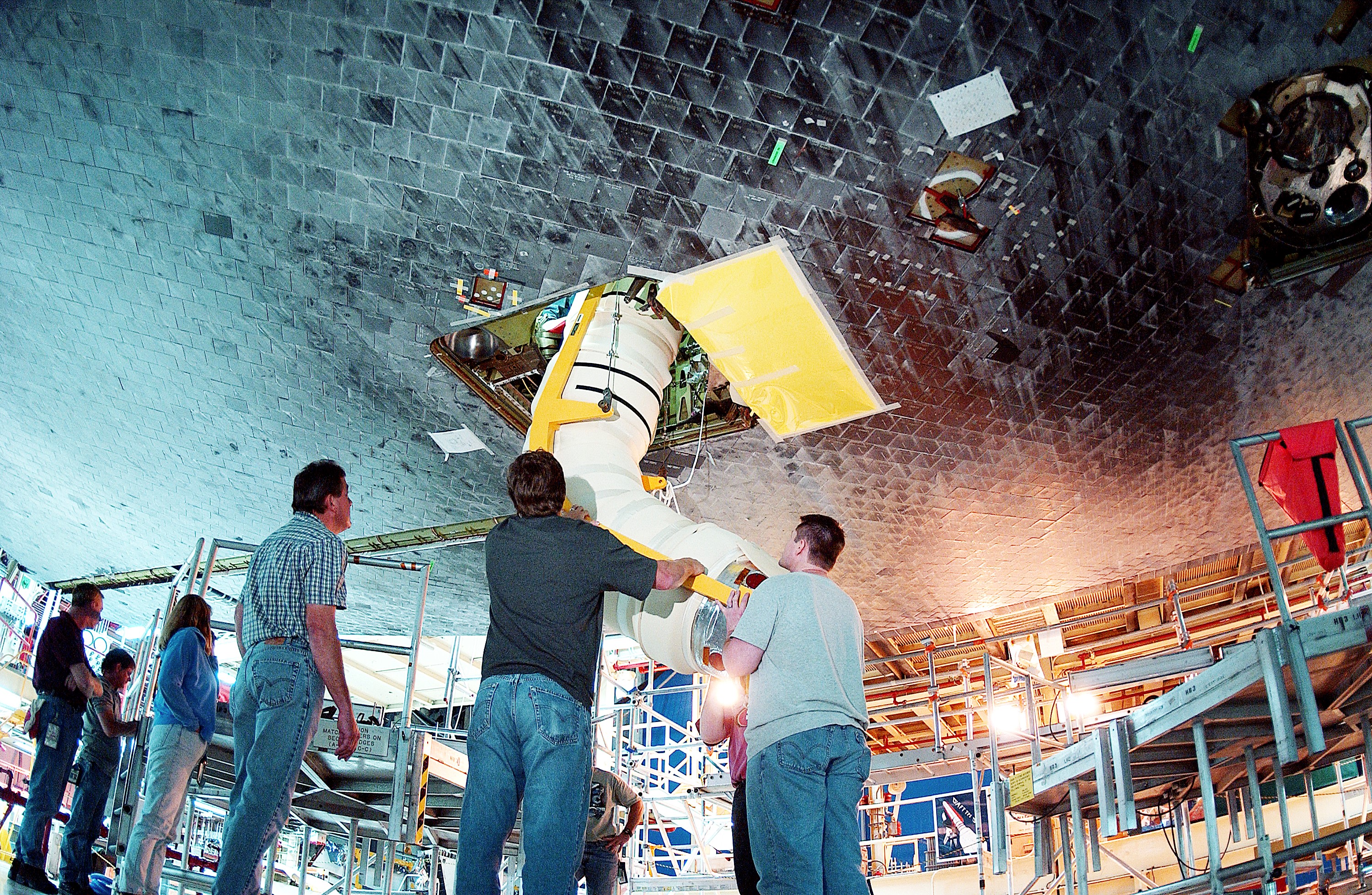 KENNEDY SPACE CENTER, FLA. - In the Orbiter Processing Facility, workers install the liquid oxygen feedline for the 17-inch disconnect on orbiter Discovery. The 17-inch liquid oxygen and liquid hydrogen disconnects provide the propellant feed interface from the external tank to the orbiter main propulsion system and the three Shuttle main engines.