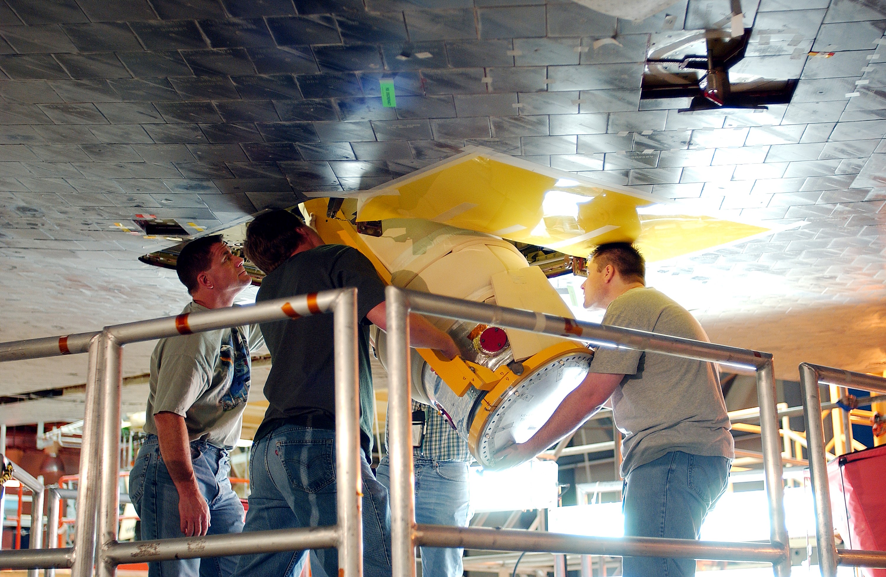 KENNEDY SPACE CENTER, FLA. - Workers in the Orbiter Processing Facility insert the liquid oxygen feedline for the 17-inch disconnect in the orbiter Discovery. The 17-inch liquid oxygen and liquid hydrogen disconnects provide the propellant feed interface from the external tank to the orbiter main propulsion system and the three Shuttle main engines.
