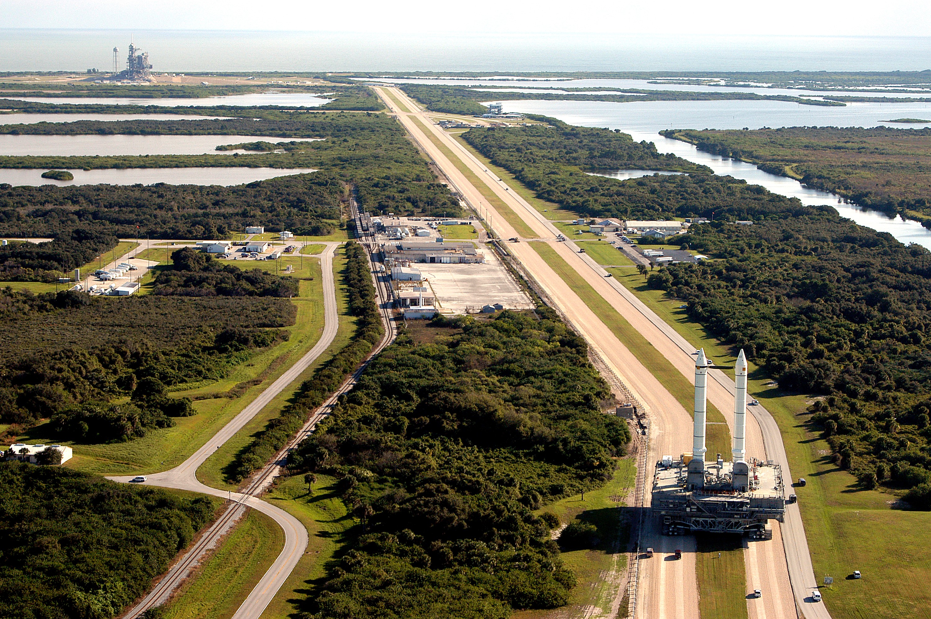 KENNEDY SPACE CENTER, FLA. - The crawler transporter slowly moves the Mobile Launcher Platform (MLP), carrying a set of twin solid rocket boosters, away from the Vehicle Assembly Building (VAB) in support of engineering analysis vibration tests on the crawler and MLP. In the distance, at left, is Launch Pad 39A. The water on the right of the crawlerway is the Banana River. The crawler is moving at various speeds up to 1 mph in an effort to achieve vibration data gathering goals as it leaves the VAB and then returns. The boosters are braced at the top for stability. The primary purpose of these rollout tests is to gather data to develop future maintenance requirements on the transport equipment and the flight hardware. Various parts of the MLP and crawler transporter have been instrumented with vibration data collection equipment.