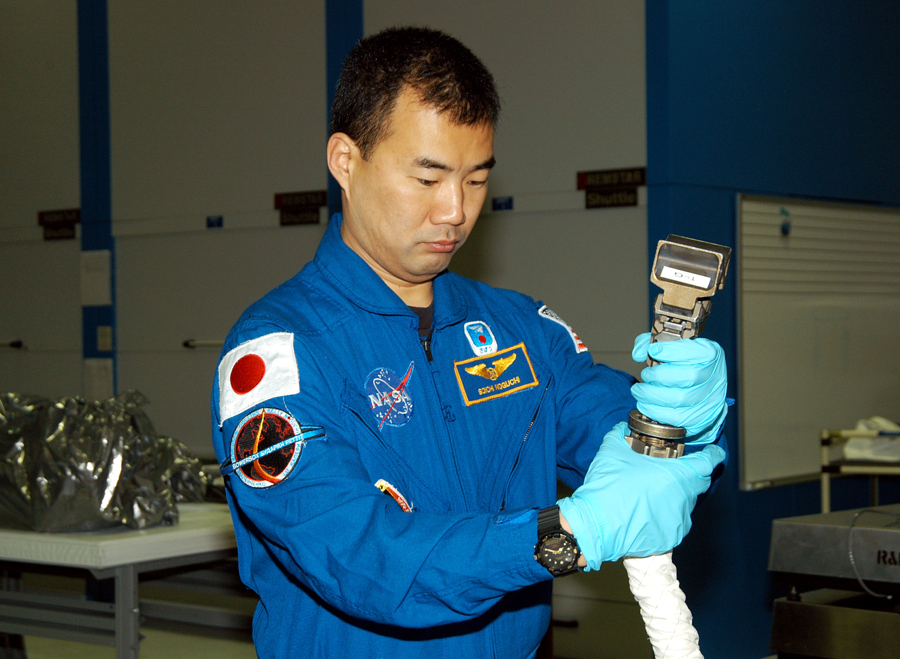 KENNEDY SPACE CENTER, FLA. - STS-114 Mission Specialist Soichi Noguchi, with the Japanese Aerospace Exploration Agency (JAXA), handles equipment that will be used on the mission. He and other crew members are at KSC for equipment familiarization. STS-114 is classified as Logistics Flight 1 to the International Space Station, delivering new supplies and replacing one of the orbital outpost’s Control Moment Gyroscopes (CMGs). STS-114 will also carry a Raffaello Multi-Purpose Logistics Module and the External Stowage Platform-2. The crew is slated to conduct at least three spacewalks: They will demonstrate repair techniques of the Shuttle’s Thermal Protection System, replace the failed CMG with one delivered by the Shuttle, and install the External Stowage Platform.