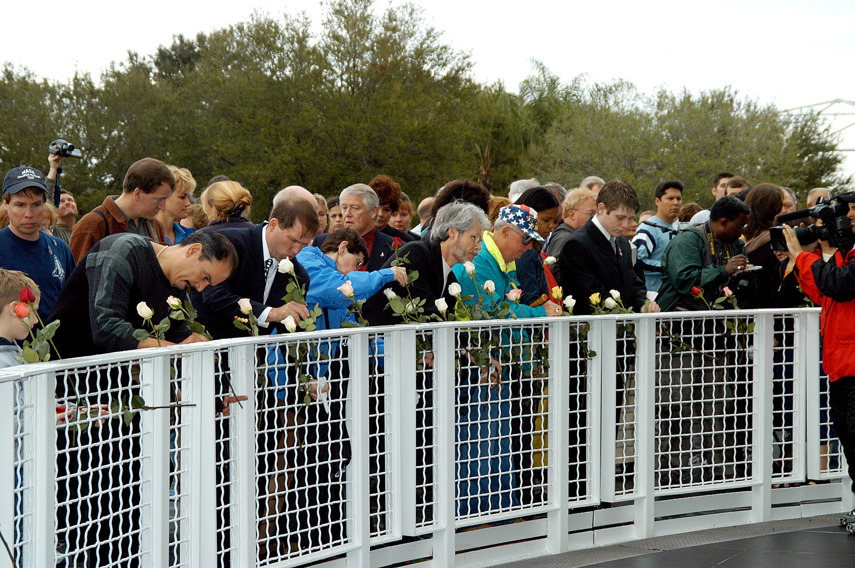 KENNEDY SPACE CENTER, FLA. - Following the memorial service for the crew of Columbia at the Space Memorial Mirror, visitors place roses in the wire mesh fence surrounding the mirror. Feb. 1 is the one-year anniversary of the loss of the crew and orbiter Columbia in a tragic accident as the ship returned to Earth following mission STS-107. Scott is a former astronaut who flew on Columbia in 1997. The public was invited to the memorial service, which included comments by Center Director Jim Kennedy and Executive Director of Florida Space Authority Winston Scott. Scott is a former astronaut who flew on Columbia in 1997.