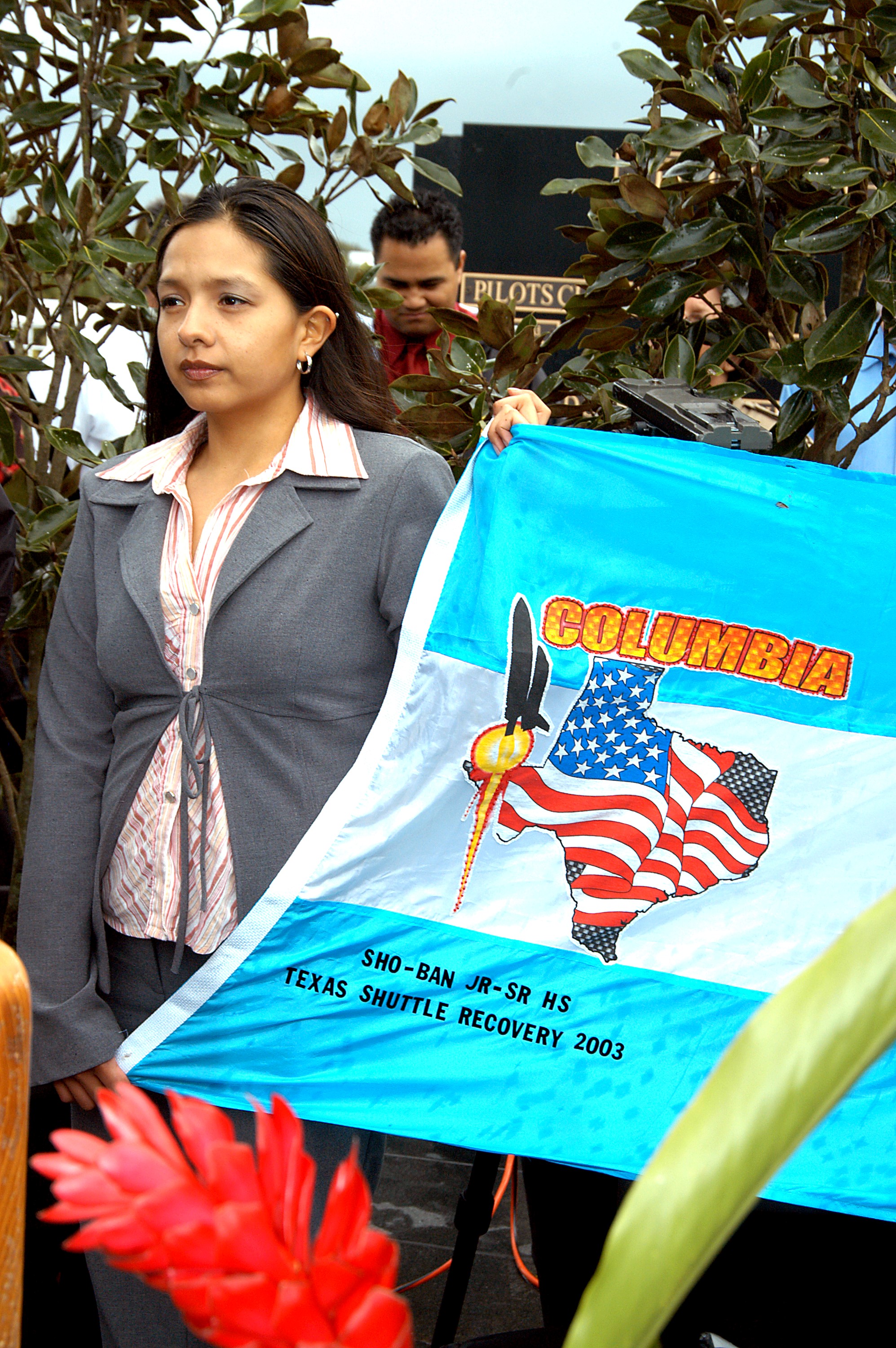 KENNEDY SPACE CENTER, FLA. - A student from Shoshone-Bannock Junior-Senior High School, Fort Hall, Idaho, holds part of a flag presented by dancers from the Shoshone-Bannock Native American community, Fort Hall, Idaho, commemorating the orbiter Columbia and her crew. The dancers performed a healing ceremony during the memorial service held at the Space Memorial Mirror for the crew of Columbia. Feb. 1 is the one-year anniversary of the loss of the crew and orbiter Columbia in a tragic accident as the ship returned to Earth following mission STS-107. Students and staff of the Shoshone-Bannock Nation had an experiment on board Columbia. The public was invited to the memorial service, held in the KSC Visitor Complex, which included comments by Center Director Jim Kennedy and Executive Director of Florida Space Authority Winston Scott. Scott is a former astronaut who flew on Columbia in 1997.