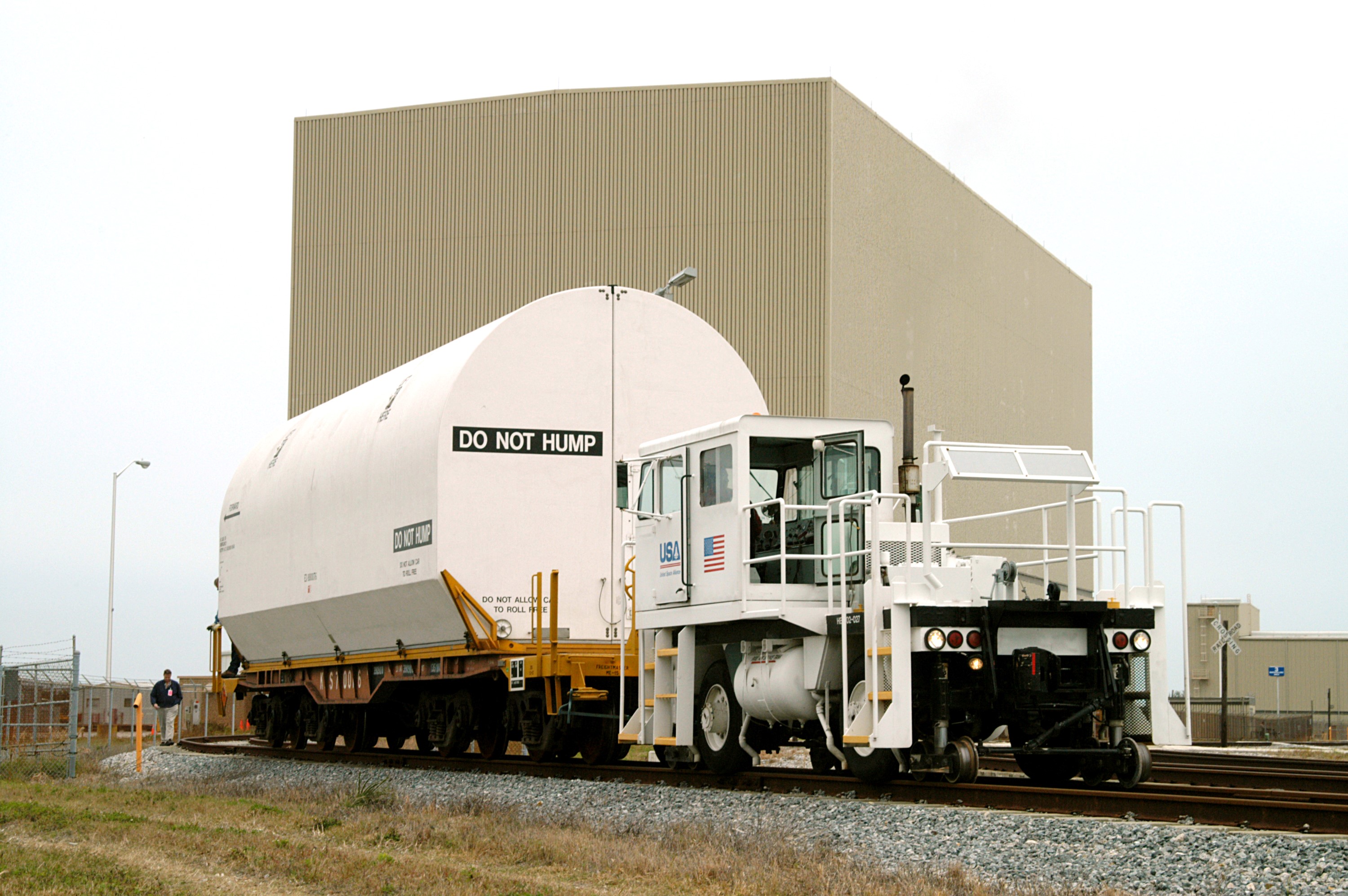 KENNEDY SPACE CENTER, FLA. - An engine pulls the container enclosing a segment of a solid rocket booster from the Rotation Processing and Surge Facility. The container will join others on the main track for a trip to Utah where the segments will undergo firing. The segments were part of the STS-114 stack. It is the first time actual flight segments that had been stacked for flight in the VAB are being returned for testing. They will undergo firing, which will enable inspectors to check the viability of the solid and verify the life expectancy for stacked segments.