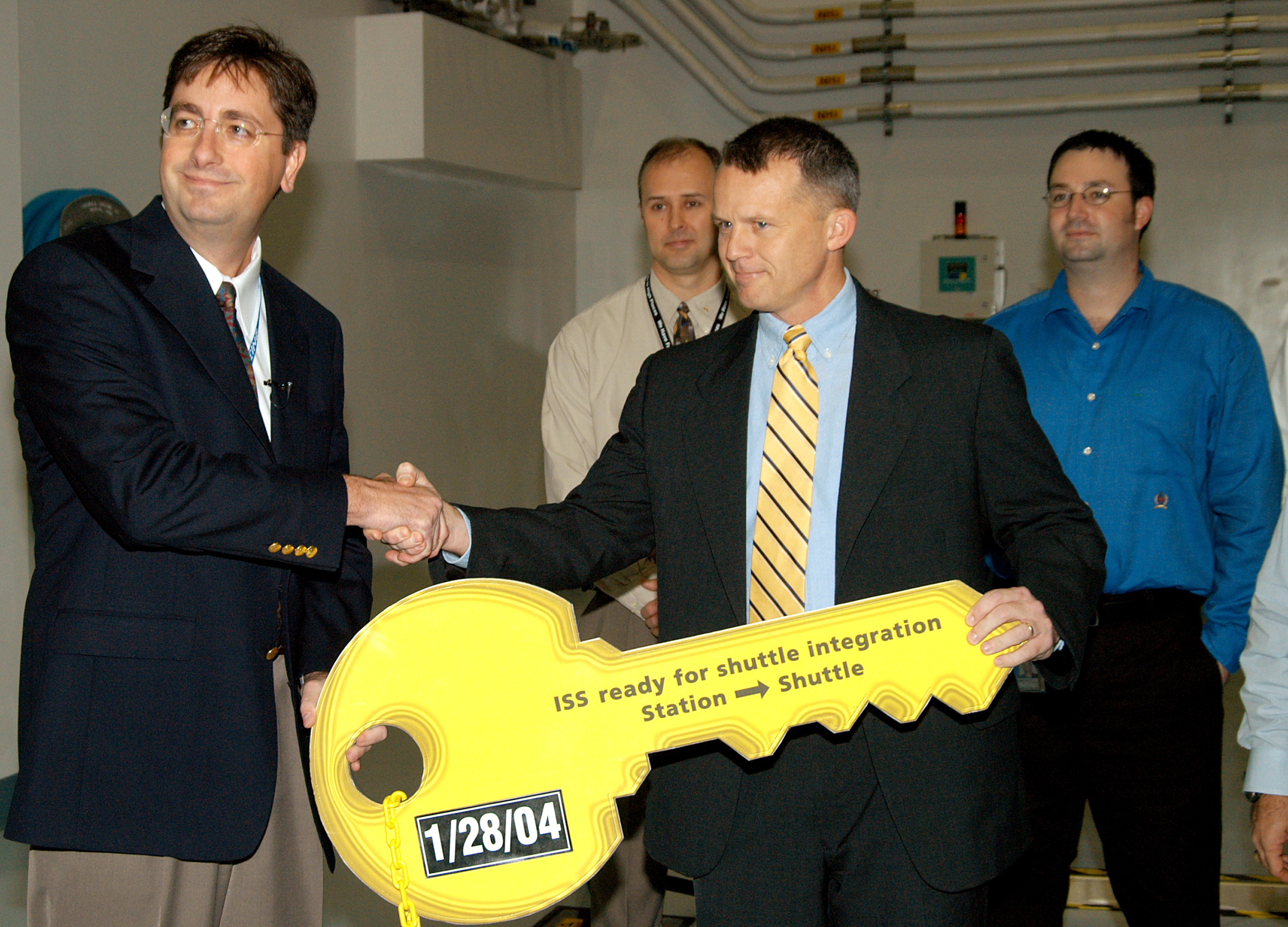 KENNEDY SPACE CENTER, FLA. - In a brief ceremony in the Space Station Processing Facility, Chuck Hardison (left), Boeing senior truss manager, turns over the “key” for the starboard truss segment S3/S4 to Scott Gahring, ISS Vehicle Office manager (acting), Johnson Space Center. The trusses are scheduled to be delivered to the International Space Station on mission STS-117.