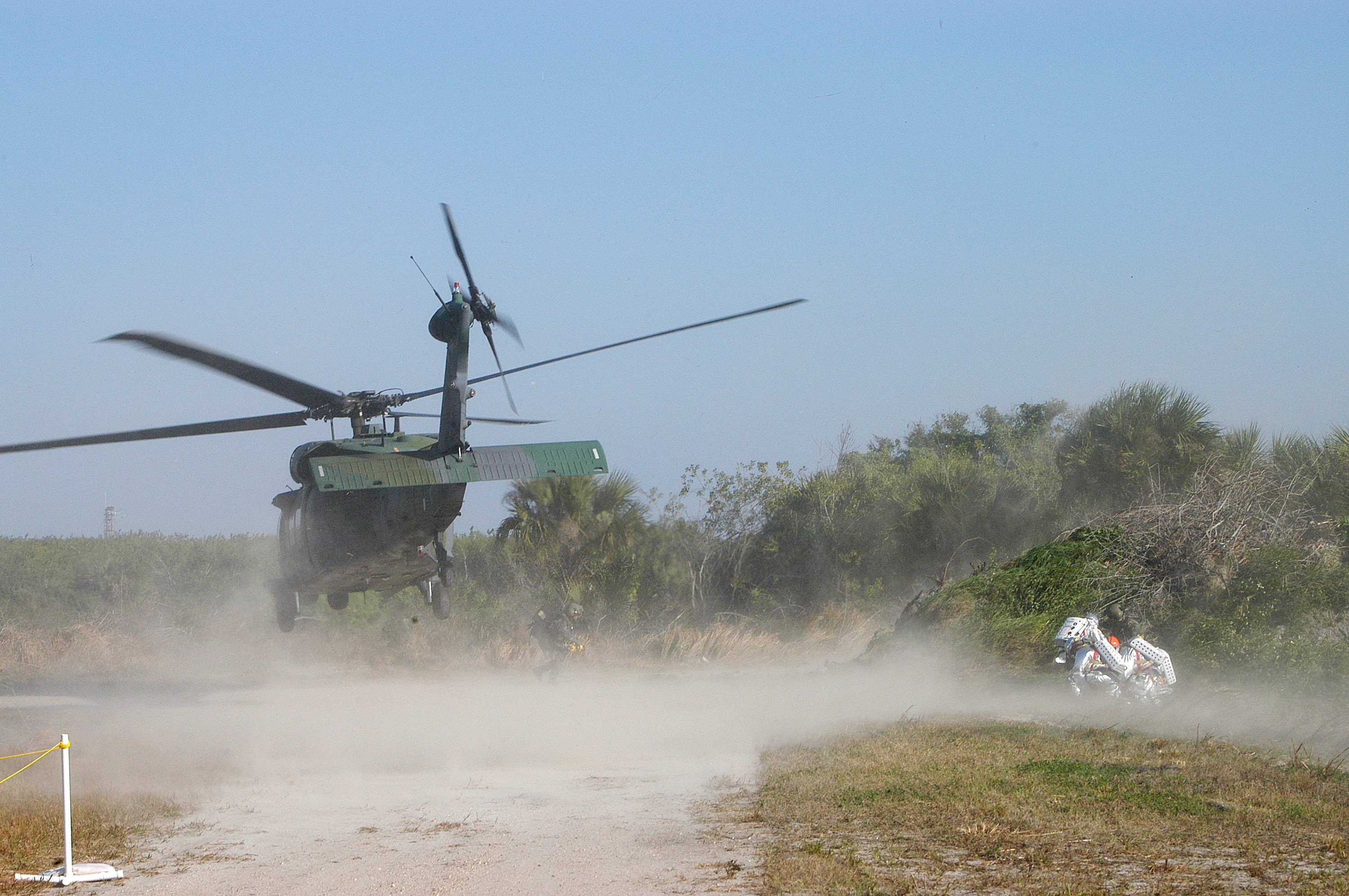 KENNEDY SPACE CENTER, FLA. - A helicopter is landing near rescue team members taking part in a “Mode VII” emergency landing simulation at Kennedy Space Center. The purpose of Mode VII is to exercise emergency preparedness personnel, equipment and facilities in rescuing astronauts from a downed orbiter and providing immediate medical attention. This simulation presents an orbiter that has crashed short of the Shuttle Landing Facility in a wooded area 2-1/2 miles south of Runway 33. Emergency crews are responding to the volunteer “astronauts” simulating various injuries inside an orbiter crew compartment mock-up. Rescuers must remove the crew, provide triage and transport to hospitals those who need further treatment. Local hospitals are participating in the exercise.