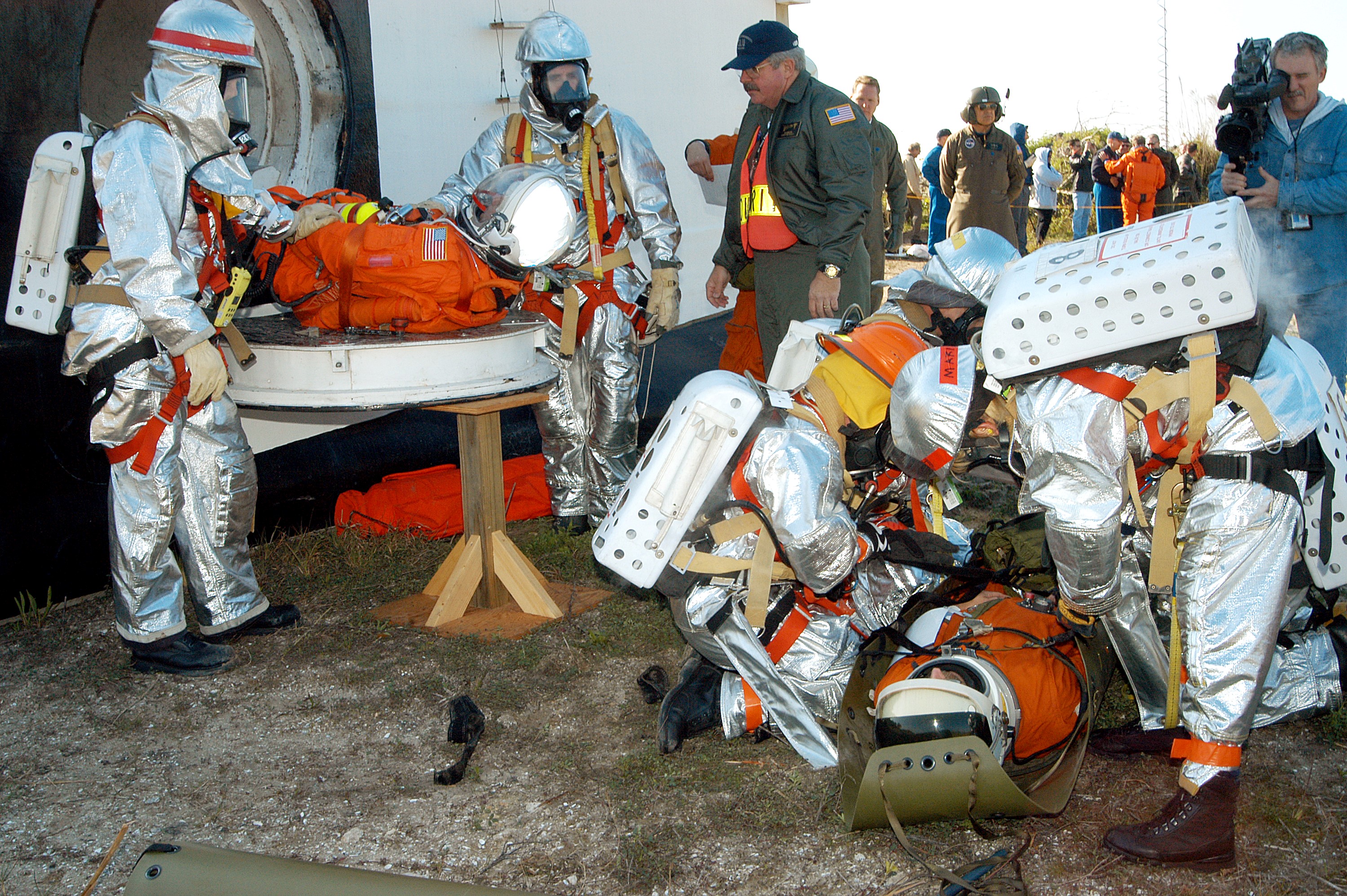 KENNEDY SPACE CENTER, FLA. - Emergency crew members help an “injured” astronaut from the orbiter crew compartment mock-up during a “Mode VII” emergency landing simulation at Kennedy Space Center. Another is on the ground. The purpose of the Mode VII is to exercise emergency preparedness personnel, equipment and facilities in rescuing astronauts from a downed orbiter and providing immediate medical attention. This simulation presents an orbiter that has crashed short of the Shuttle Landing Facility in a wooded area 2-1/2 miles south of Runway 33. Emergency crews are responding to the volunteer astronauts who are simulating various injuries. Rescuers must remove the crew, provide triage and transport to hospitals those who need further treatment. Local hospitals are participating in the exercise.