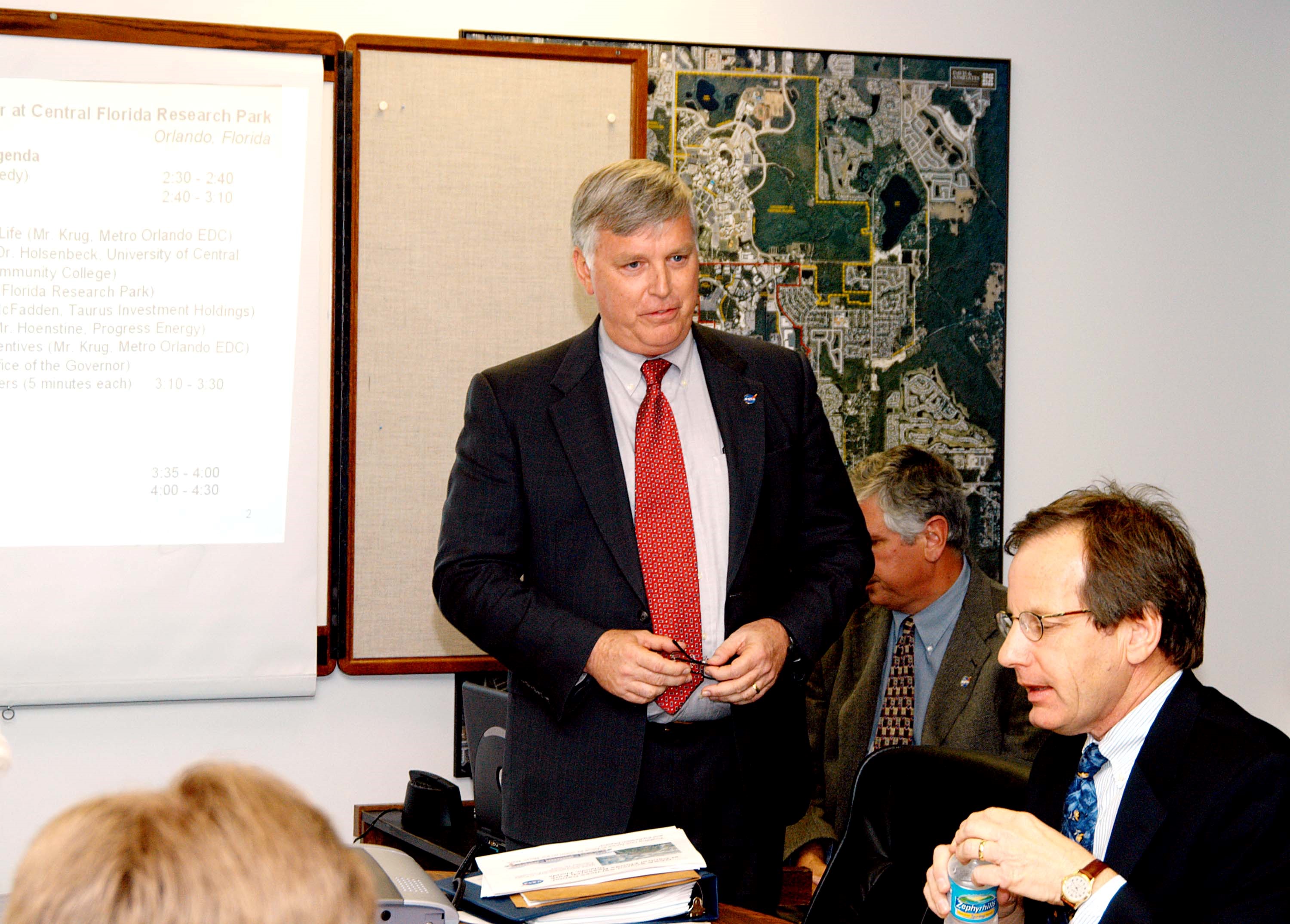 KENNEDY SPACE CENTER, FLA. - KSC Director Jim Kennedy (center) makes a presentation to NASA and other officials about the benefits of locating NASA’s new Shared Services Center in the Central Florida Research Park, near Orlando. Central Florida leaders are proposing the research park as the site for the NASA Shared Services Center. The center would centralize NASA’s payroll, accounting, human resources, facilities and procurement offices that are now handled at each field center. The consolidation is part of the One NASA focus. Six sites around the U.S. are under consideration by NASA.