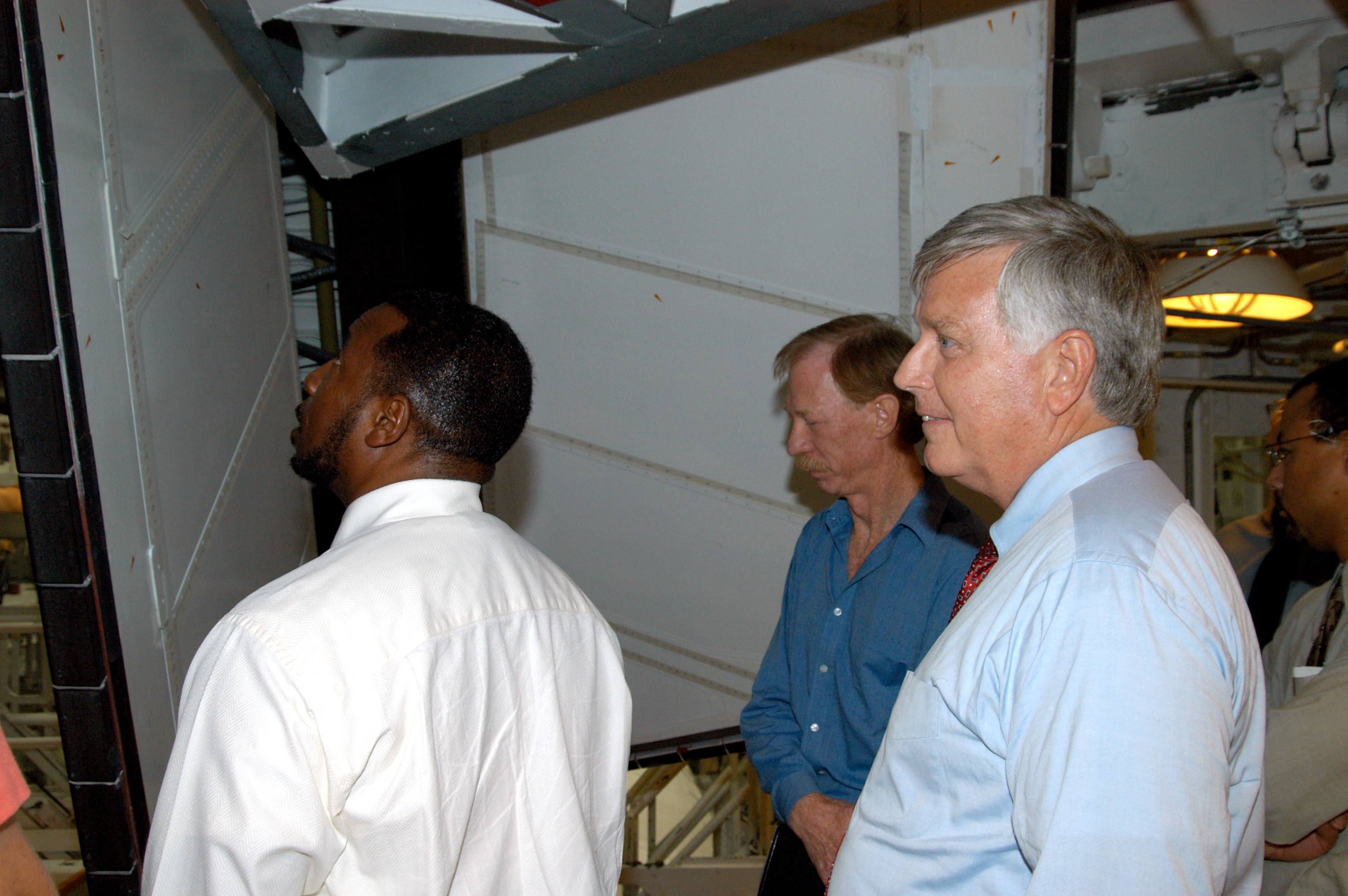 KENNEDY SPACE CENTER, FLA. - On a tour of the Orbiter Processing Facility, Center Director Jim Kennedy (right) and Deputy Director Woodrow Whitlow Jr. (left) look at rudder speed brake panels on Endeavour In the background is Tom Roberts, who is with United Space Alliance. Endeavour is in its Orbiter Major Modification period, which began in December 2003.