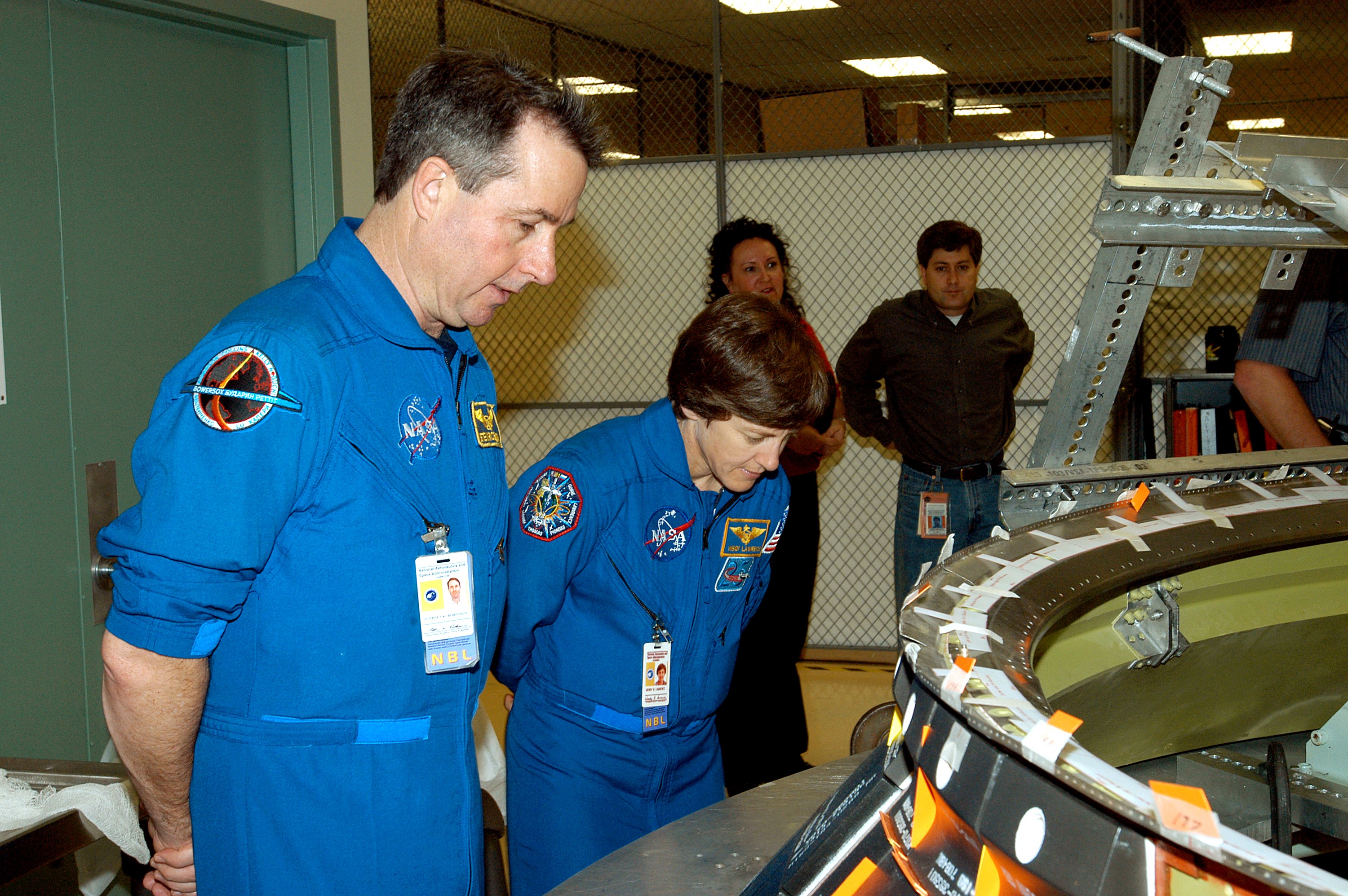KENNEDY SPACE CENTER, FLA. - Members of the STS-114 crew spend time in the Orbiter Processing Facility becoming familiar with Shuttle and mission equipment. Mission Specialists Stephen Robinson (left) and Wendy Lawrence (right) look at an engine eyelet, which serves as part of the thermal protection system on an orbiter. The STS-114 mission is Logistics Flight 1, which is scheduled to deliver supplies and equipment and the external stowage platform to the International Space Station.
