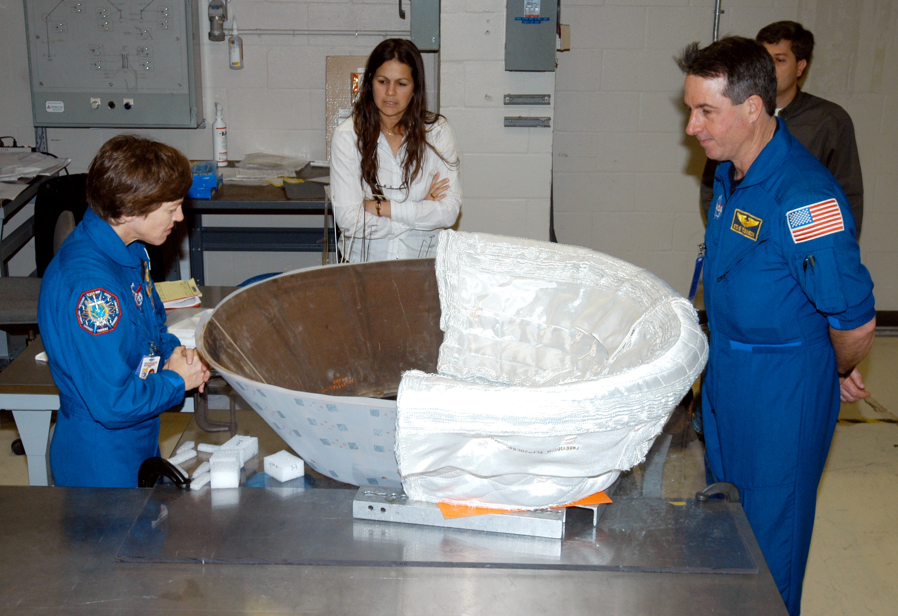 KENNEDY SPACE CENTER, FLA. - STS-114 Mission Specialists Wendy Lawrence (left) and Stephen Robinson (right) look at the insert for Discovery’s nose cap that is being fitted with thermal protection system insulation blankets. The mission crew is spending time becoming familiar with Shuttle and mission equipment. The mission is Logistics Flight 1, which is scheduled to deliver supplies and equipment plus the external stowage platform to the International Space Station.