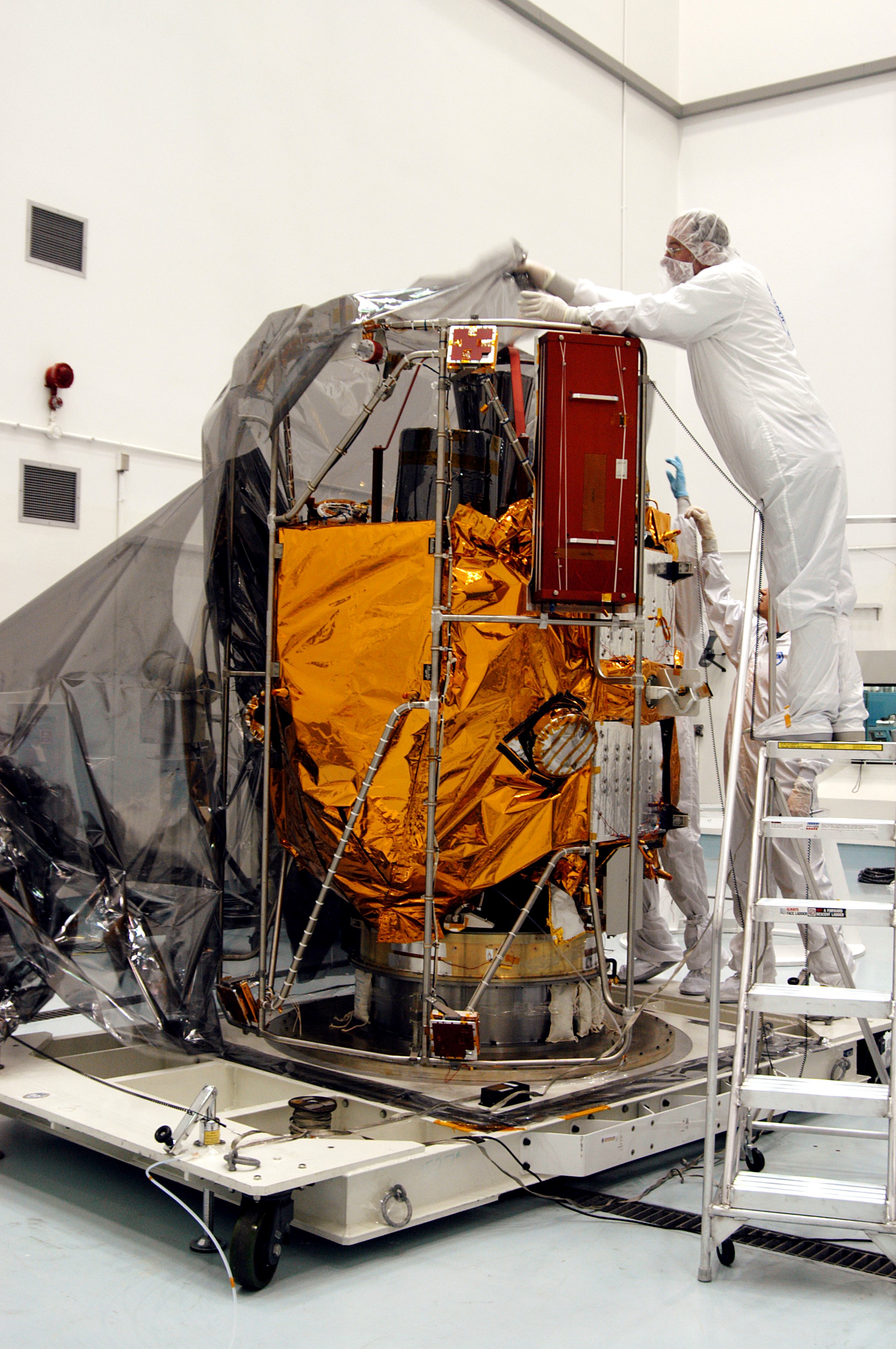 KENNEDY SPACE CENTER, FLA. - In the high bay clean room at the Astrotech Space Operations processing facilities near KSC, workers remove the protective cover from NASA’s MESSENGER spacecraft. Employees of the Johns Hopkins University Applied Physics Laboratory, builders of the spacecraft, will perform an initial state-of-health check. Then processing for launch can begin, including checkout of the power systems, communications systems and control systems. The thermal blankets will also be attached for flight. MESSENGER - short for MErcury Surface, Space ENvironment, GEochemistry and Ranging - will be launched May 11 on a six-year mission aboard a Boeing Delta II rocket. Liftoff is targeted for 2:26 a.m. EDT on Tuesday, May 11.