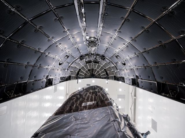 Upward-looking view from the base of the payload fairing showing the Roman Space Telescope beneath the curved, segmented fairing interior.