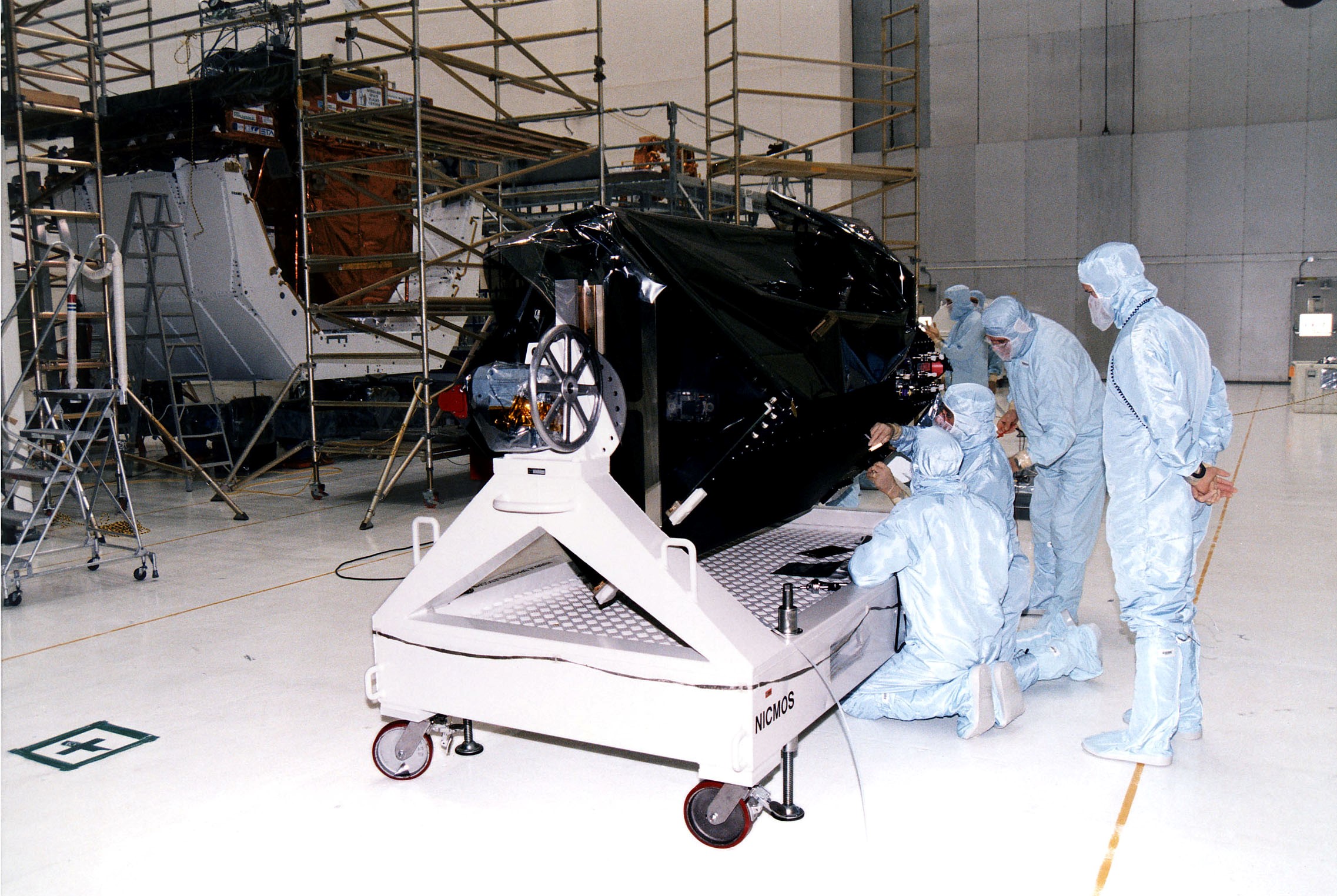 KENNEDY SPACE CENTER, FLA. - Workers in KSC's Vertical Processing Facility inspect the Near Infrared Camera and Multi-Object Spectrometer (NICMOS) on its handling fixture. NICMOS is one of two new scientific instruments that will replace two outdated instruments on the Hubble Space Telescope (HST). NICMOS will provide HST with the capability for infrared imaging and spectroscopic observations of astronomical targets. The refrigerator-sized NICMOS also is HST's first cryogenic instrument — its sensitive infrared detectors must operate at very cold temperatures of minus 355 degrees Fahrenheit or 58 degrees Kelvin. NICMOS will be installed in Hubble during STS-82, the second Hubble Space Telescope servicing mission. Liftoff is targeted Feb. 11 aboard Discovery with a crew of seven.