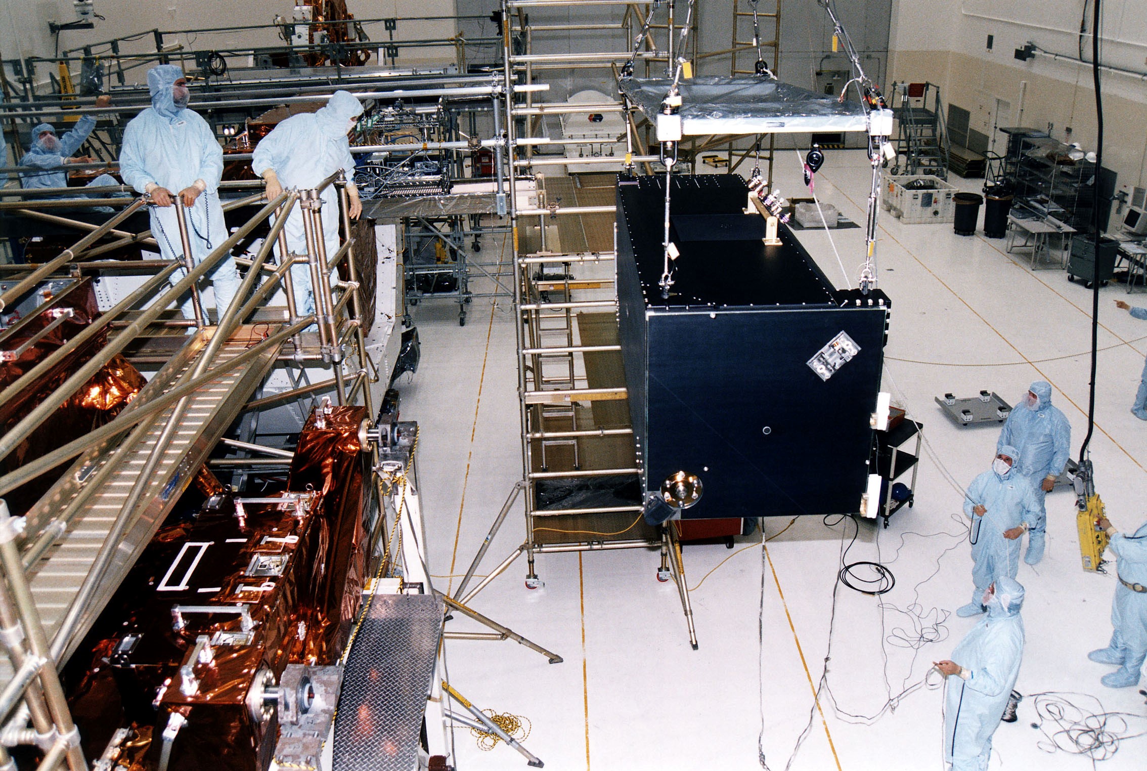 KENNEDY SPACE CENTER, FLA. - Workers in KSC's Vertical Processing Facility lift the Near Infrared Camera and Multi-Object Spectrometer (NICMOS) prior to its installation in the Second Axial Carrier. NICMOS is one of two new scientific instruments that will replace two outdated instruments on the Hubble Space Telescope (HST). NICMOS will provide HST with the capability for infrared imaging and spectroscopic observations of astronomical targets. The refrigerator-sized NICMOS also is HST's first cryogenic instrument — its sensitive infrared detectors must operate at very cold temperatures of minus 355 degrees Fahrenheit or 58 degrees Kelvin. NICMOS will be installed in Hubble during STS-82, the second Hubble Space Telescope servicing mission. Liftoff is targeted Feb. 11 aboard Discovery with a crew of seven.