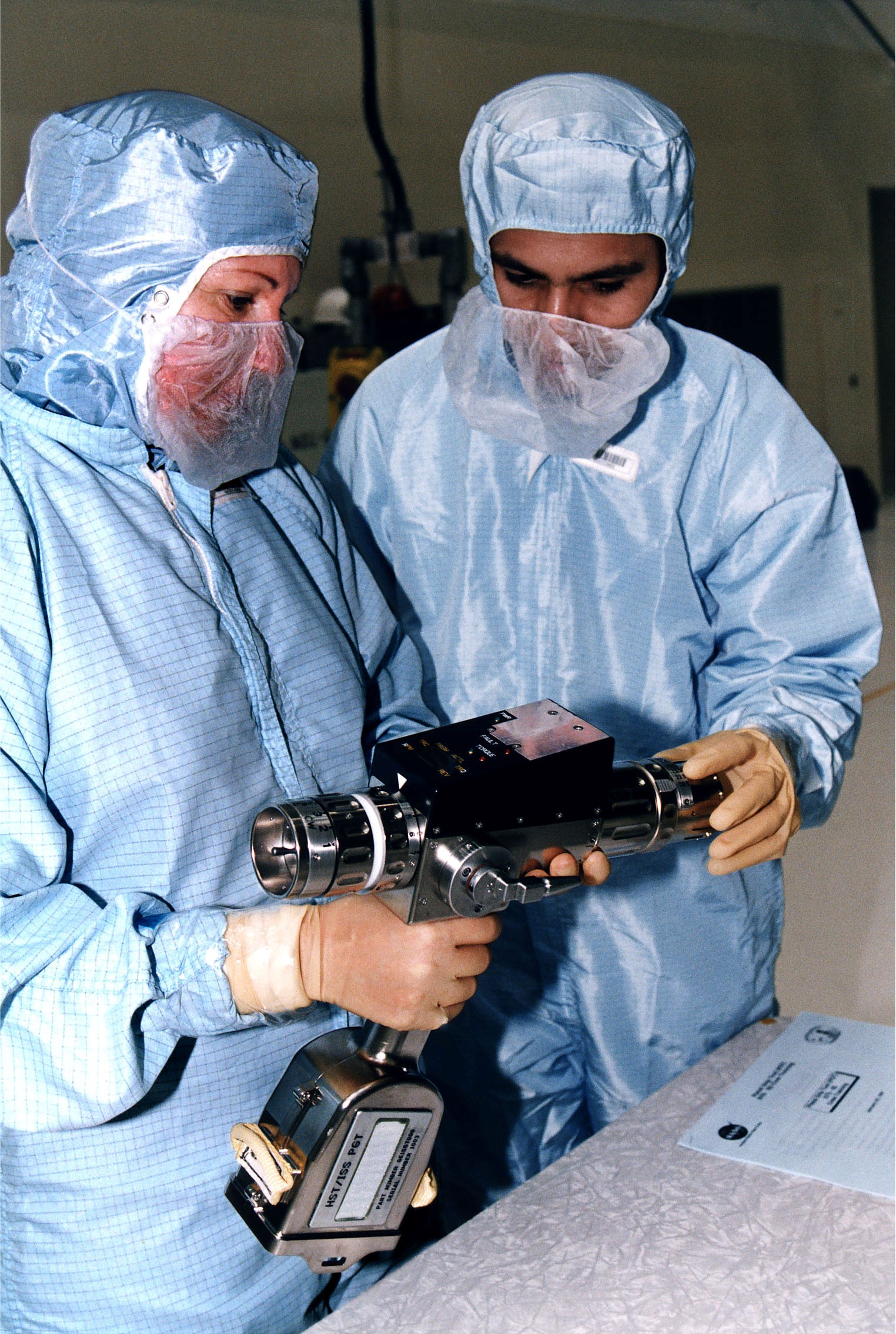 KENNEDY SPACE CENTER, FLA. - In KSC's Vertical Processing Facility, Louise Kleba of the Vehicle Integration Test Team (VITT) and engineer Devin Tailor of Goddard Space Flight Center examine the Pistol Grip Tool (PGT), which was designed for use by astronauts during spacewalks. The PGT is a self-contained, micro-processor controlled, battery-powered tool. It also can be used as a nonpowered ratchet wrench. The experiences of the astronauts on the first Hubble Space Telescope (HST) servicing mission led to recommendations for this smaller, more efficient tool for precision work during spacewalks. The PGT will be used on the second HST servicing mission, STS-82. Liftoff aboard Discovery is scheduled Feb. 11.