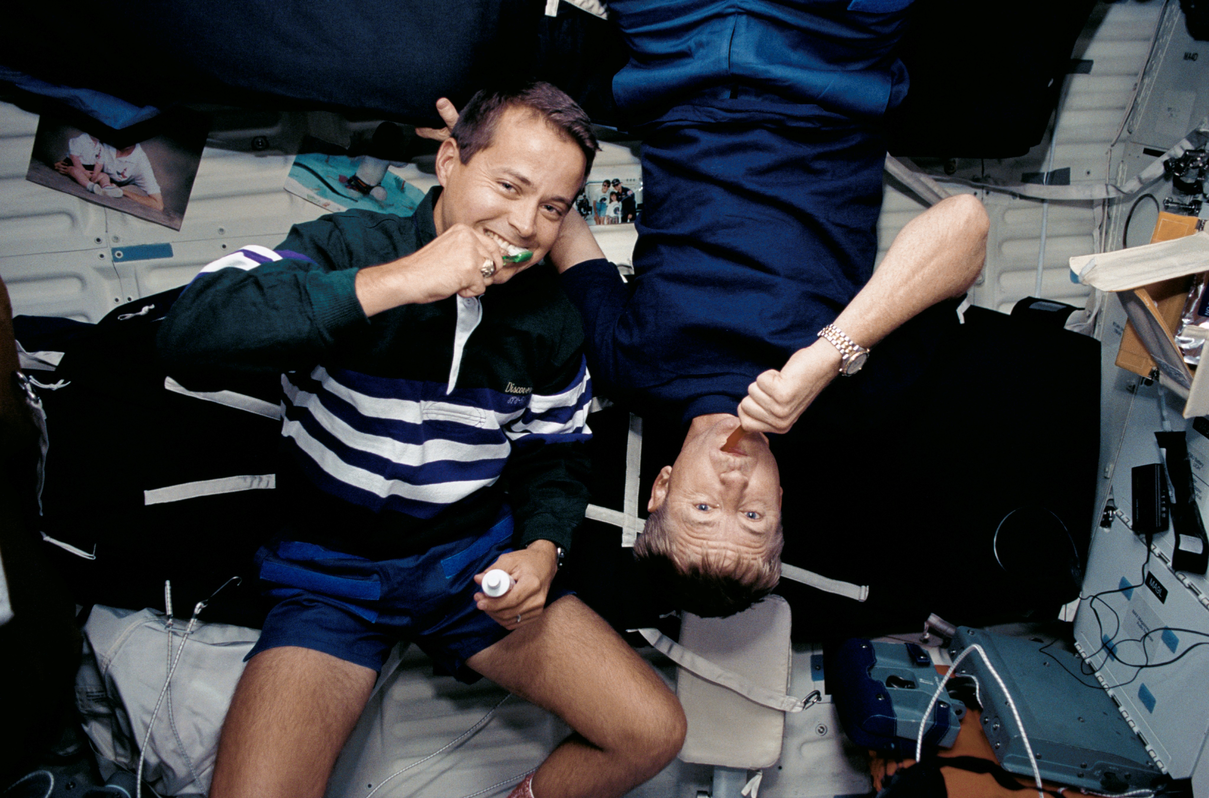 Astronauts Culbertson and Bursch brush their teeth on Discovery's middeck