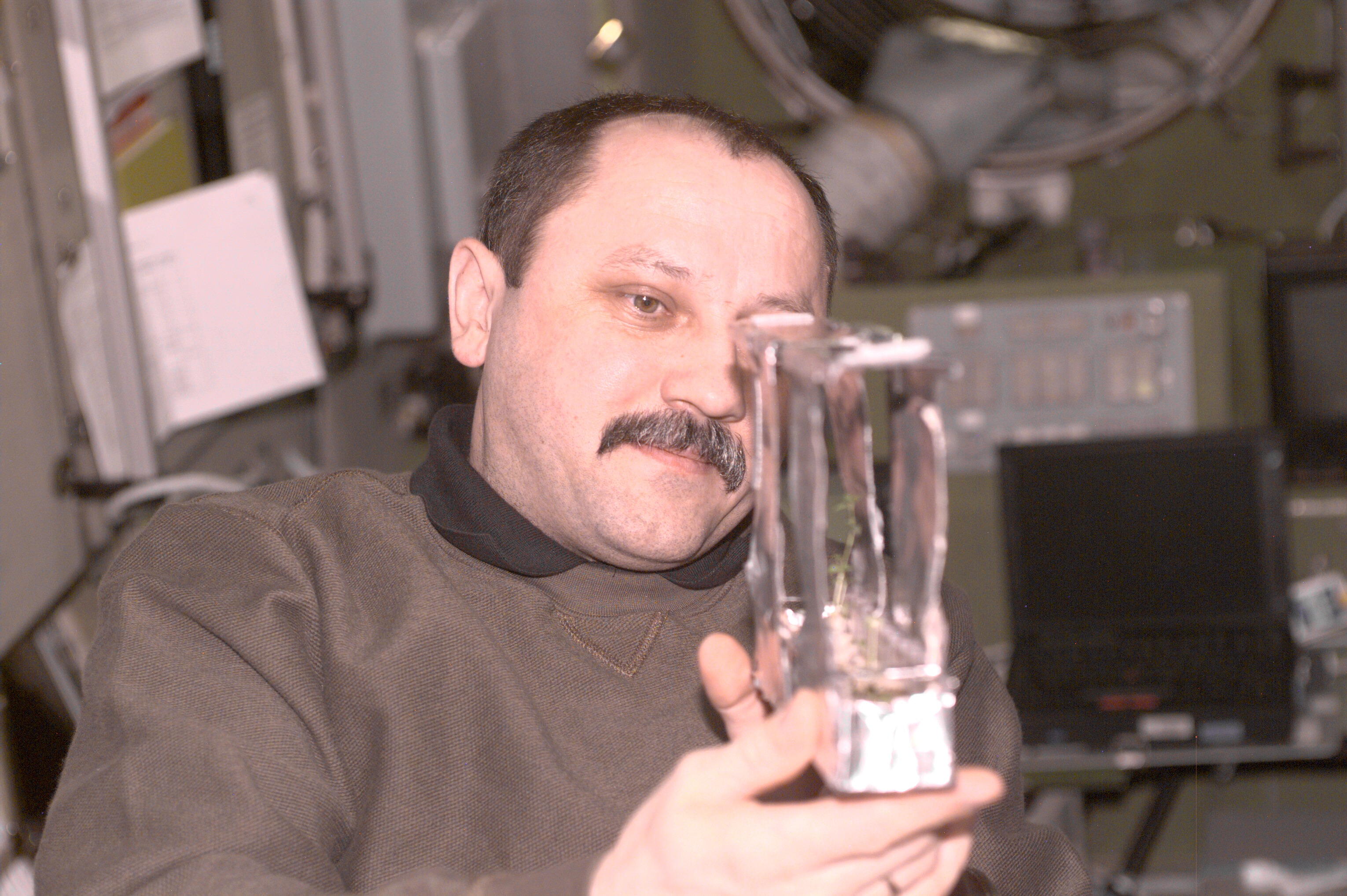 Yury Usachev examines a plant experiment in Zvezda during Expedition Three