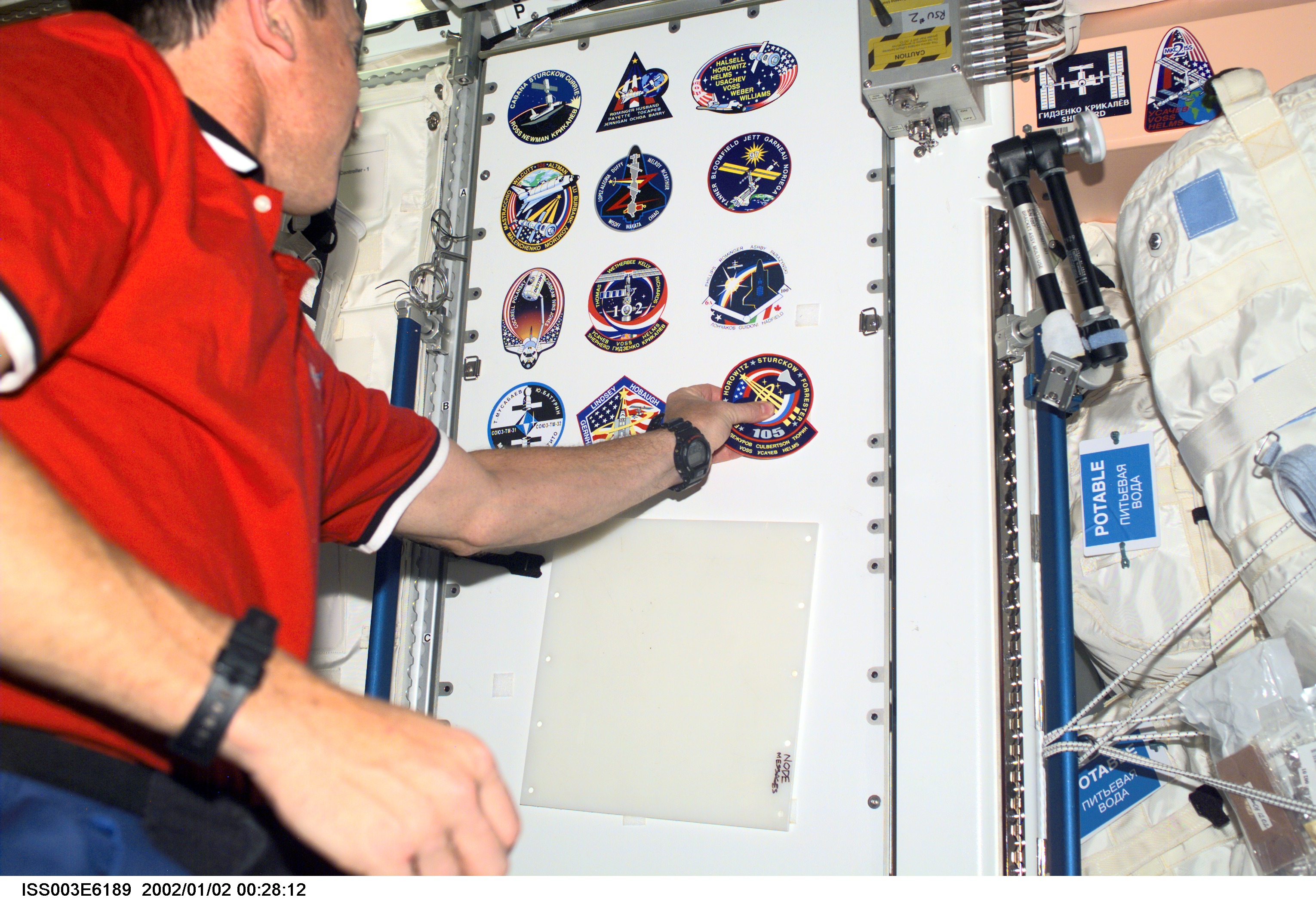 Horowitz adheres a STS-105 mission logo to a Node 1 panel